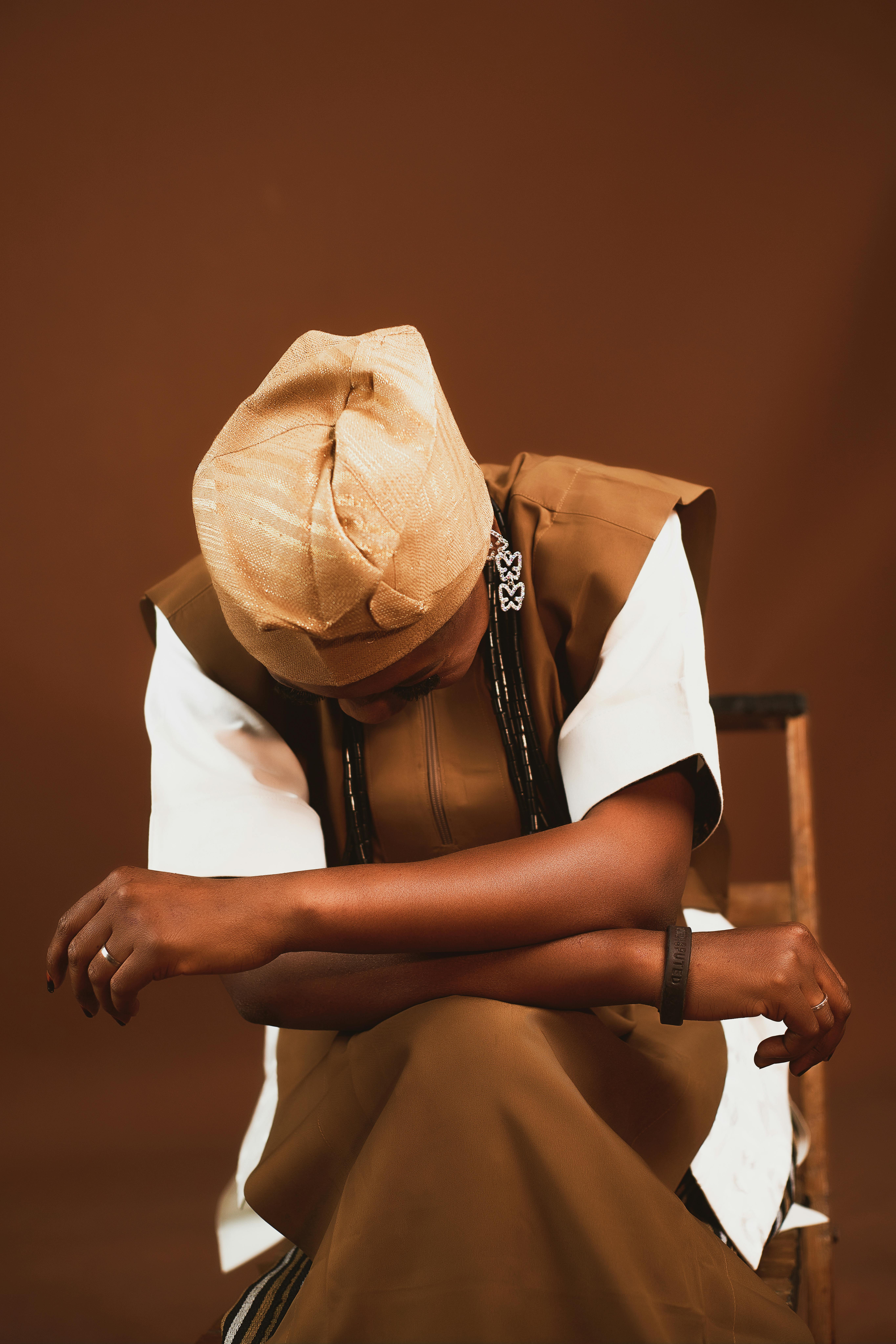 gratis Persoon in traditionele Afrikaanse kleding zit met gebogen hoofd in overpeinzing. Stockfoto