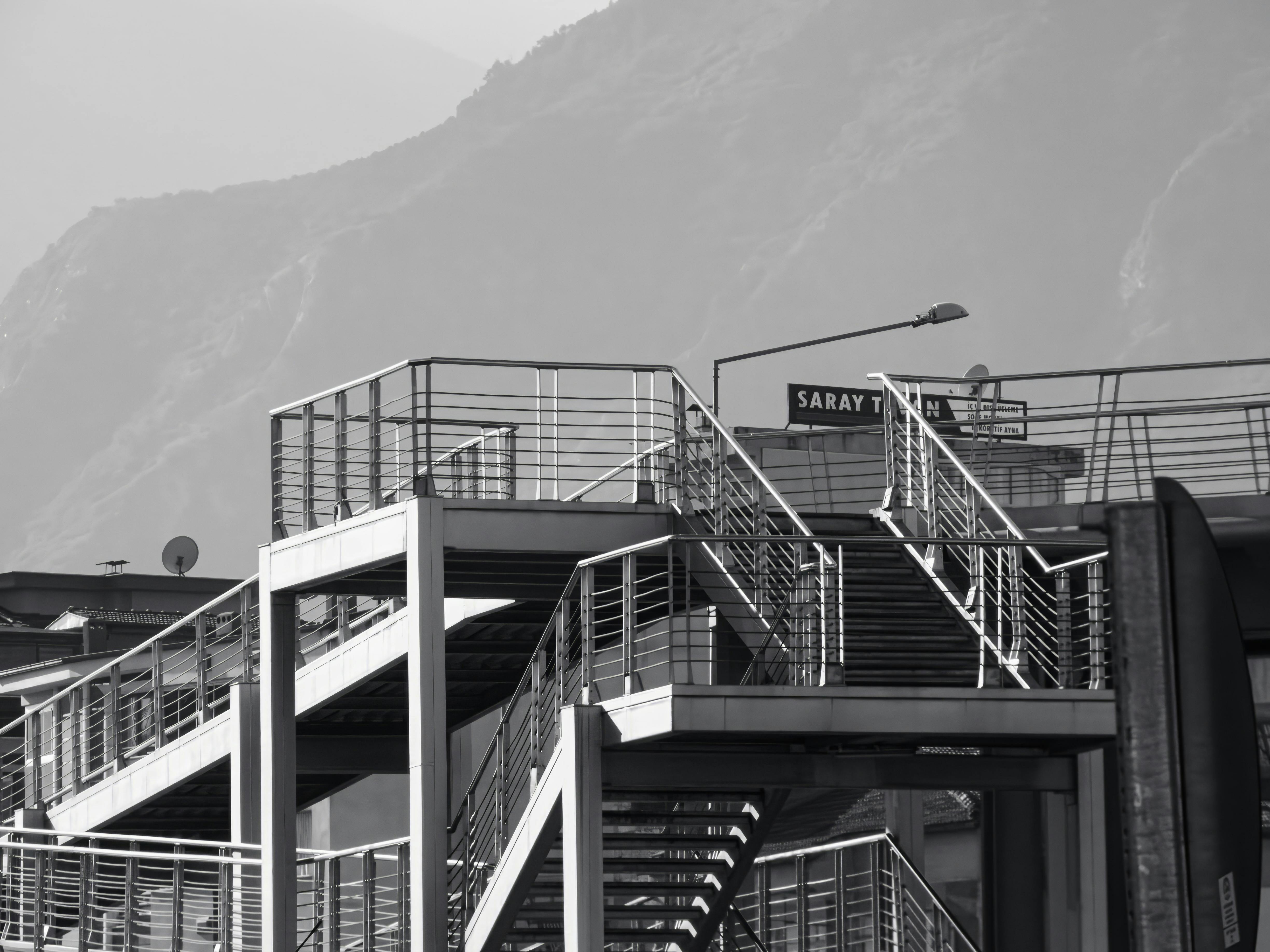 Miễn phí Ảnh đen trắng chụp cầu thang công nghiệp trước khung cảnh núi non hùng vĩ. Ảnh lưu trữ