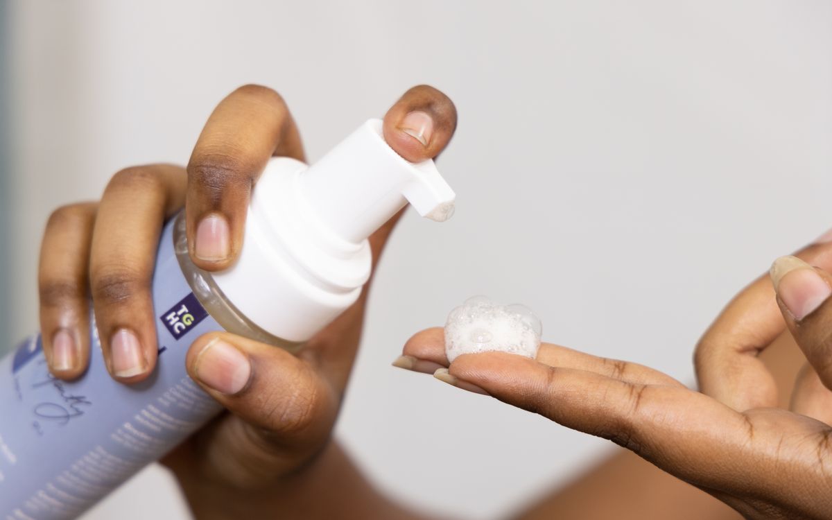 Close-up of hands dispensing soothing foaming face wash, ideal for sensitive skin care.