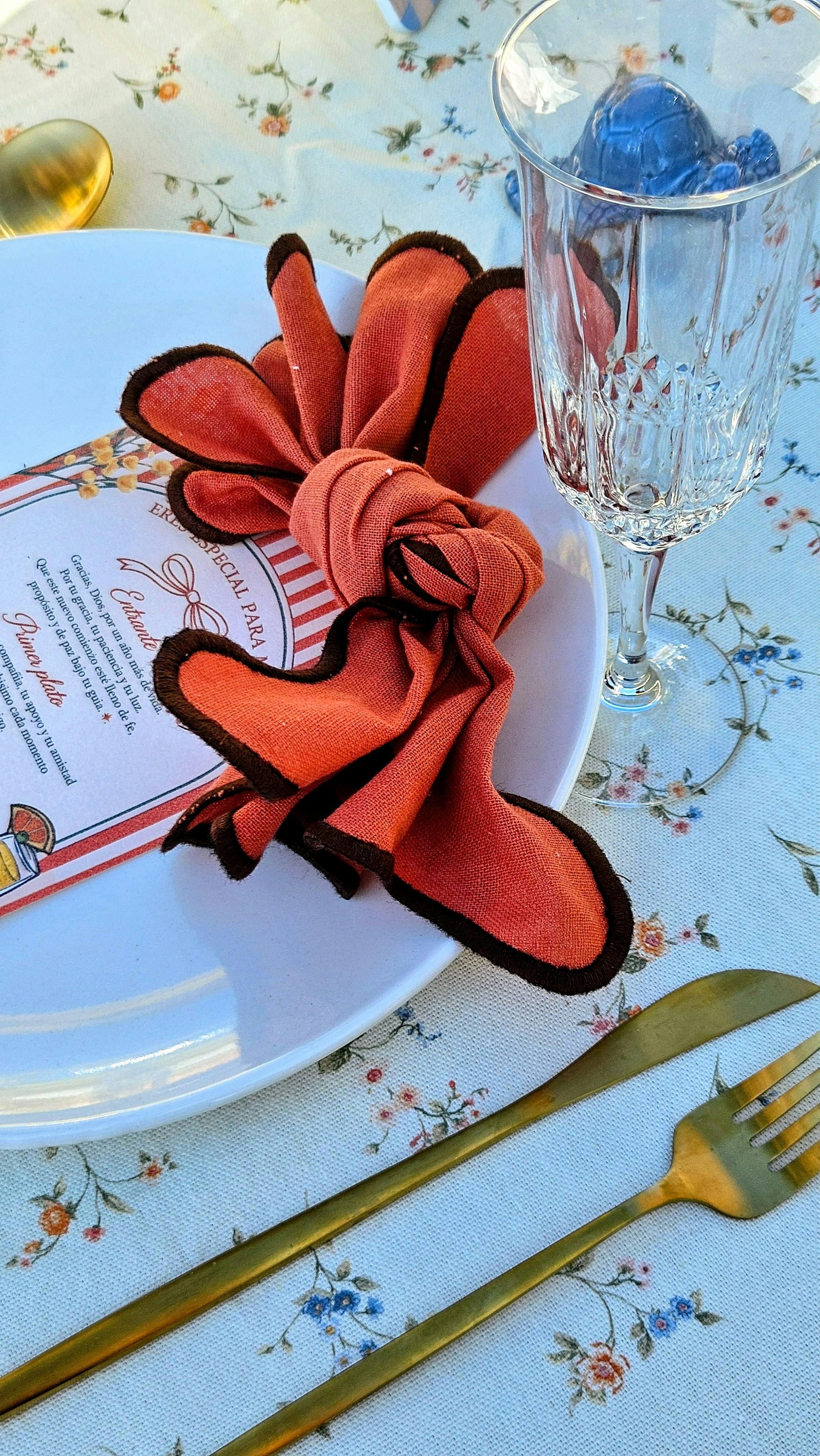 Kostnadsfria Elegant matbordsdukning med röd servett och kristallglas på blommig duk, perfekt för evenemang. Stock foto