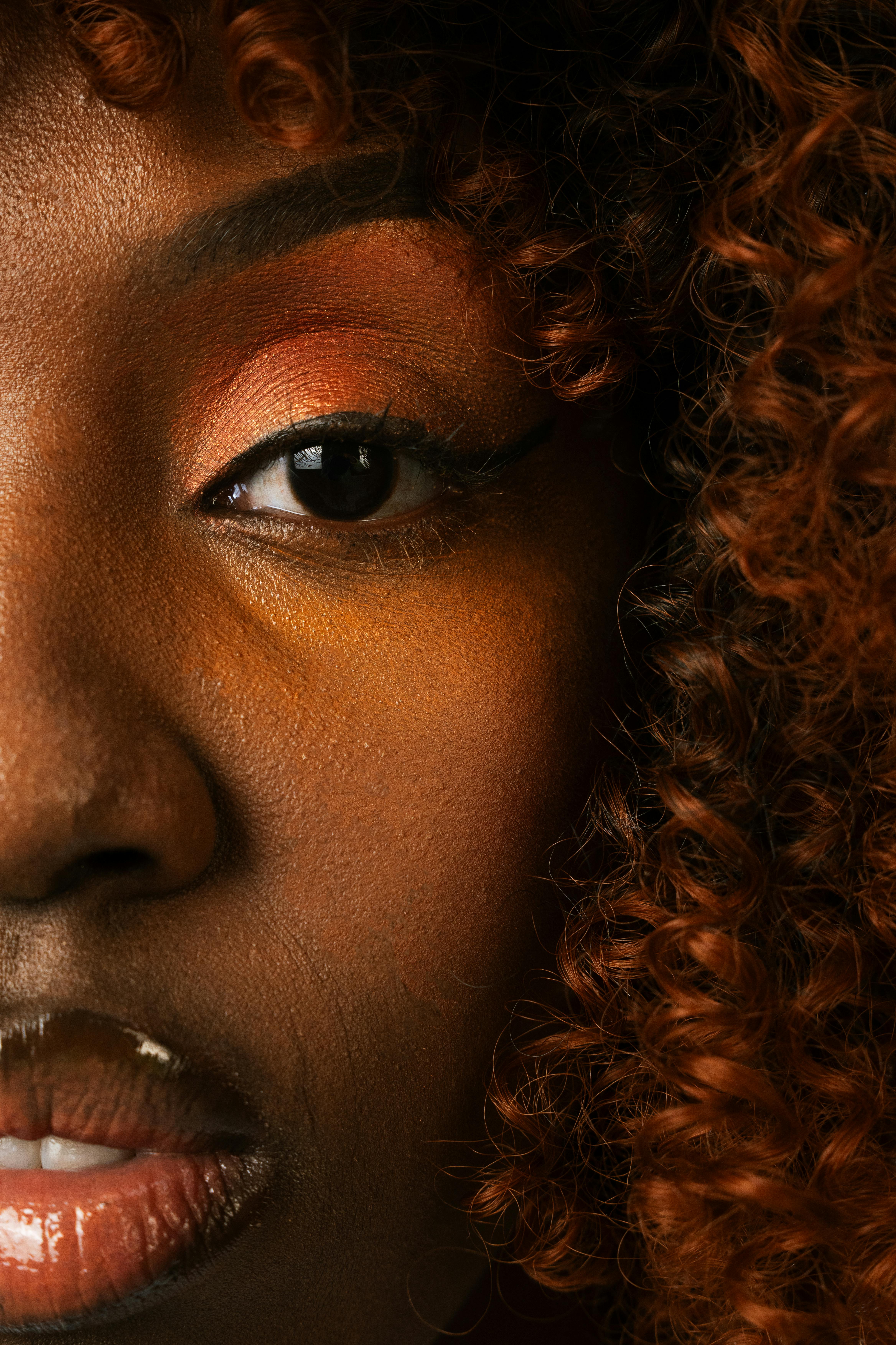 Artistic close-up portrait highlighting vibrant makeup and natural curls.