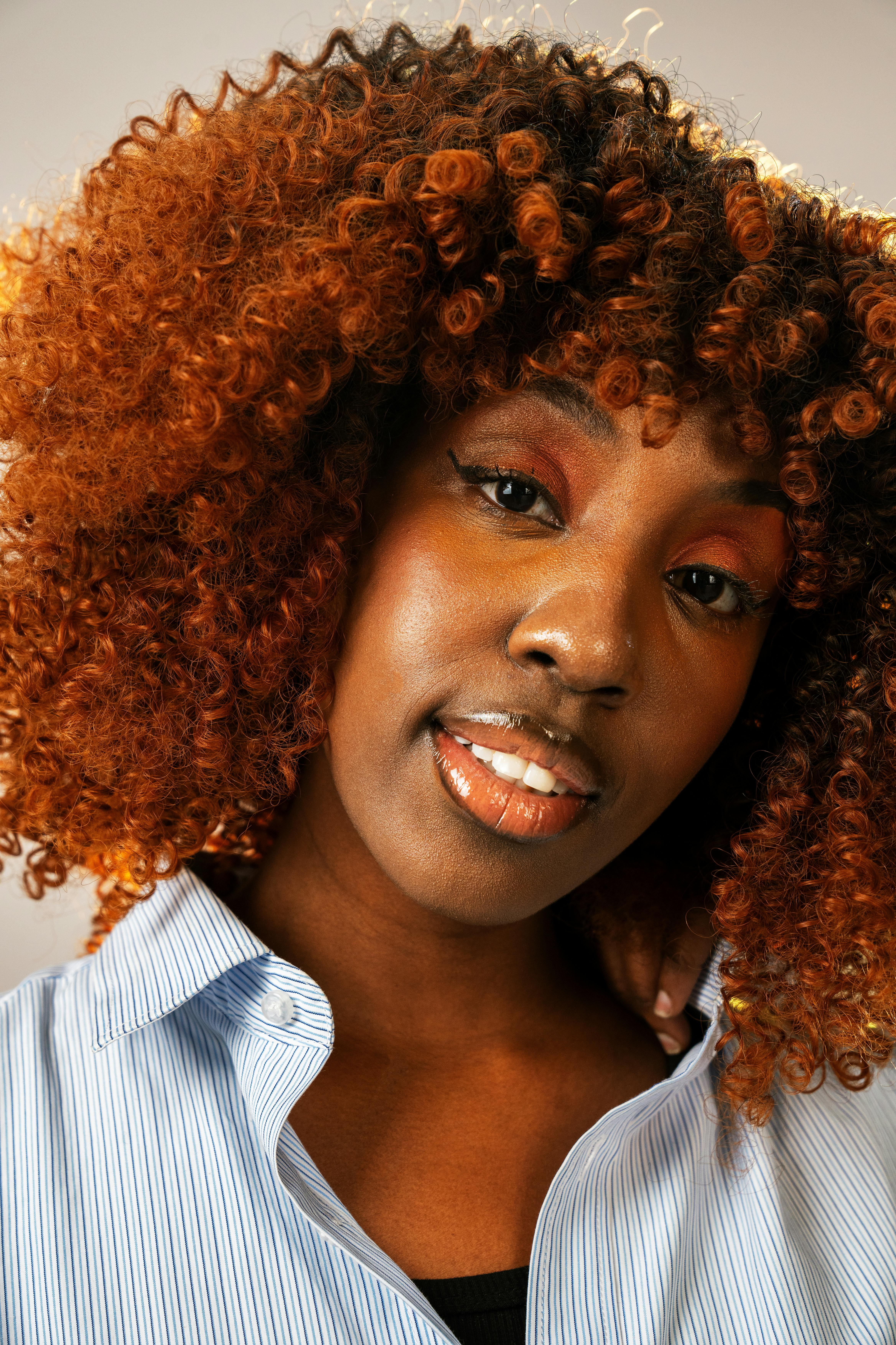 Miễn phí Ảnh chân dung cận cảnh một người phụ nữ tự tin với mái tóc xoăn trong bối cảnh studio. Ảnh lưu trữ