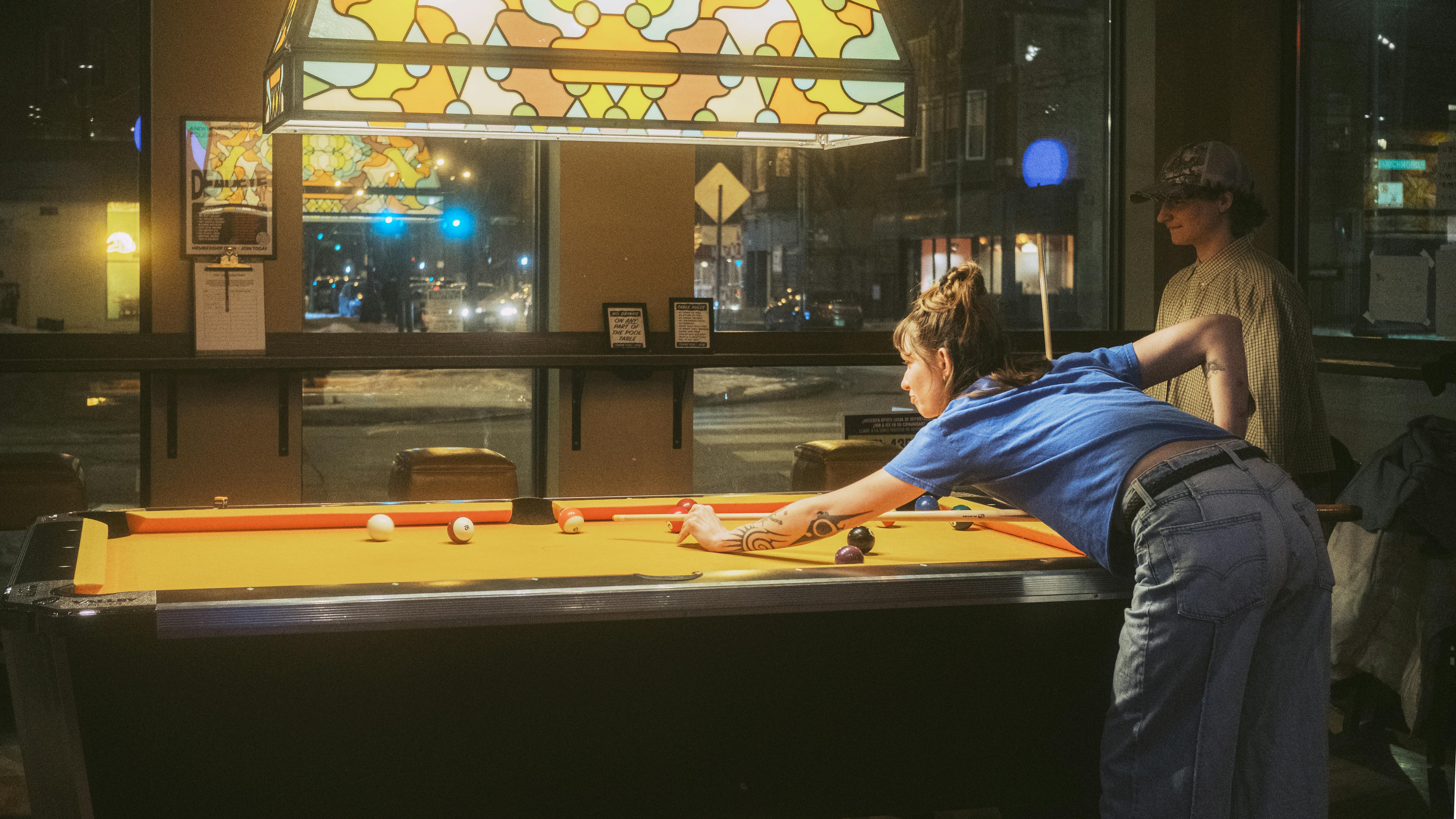 Gratis To unge voksne nyder et spil billard i en varmt oplyst, hyggelig bar. Lagerfoto