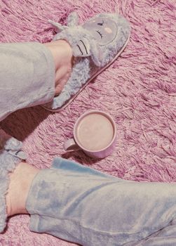 Pastel-themed cozy morning with fluffy slippers and a mug of coffee on a pink carpet.