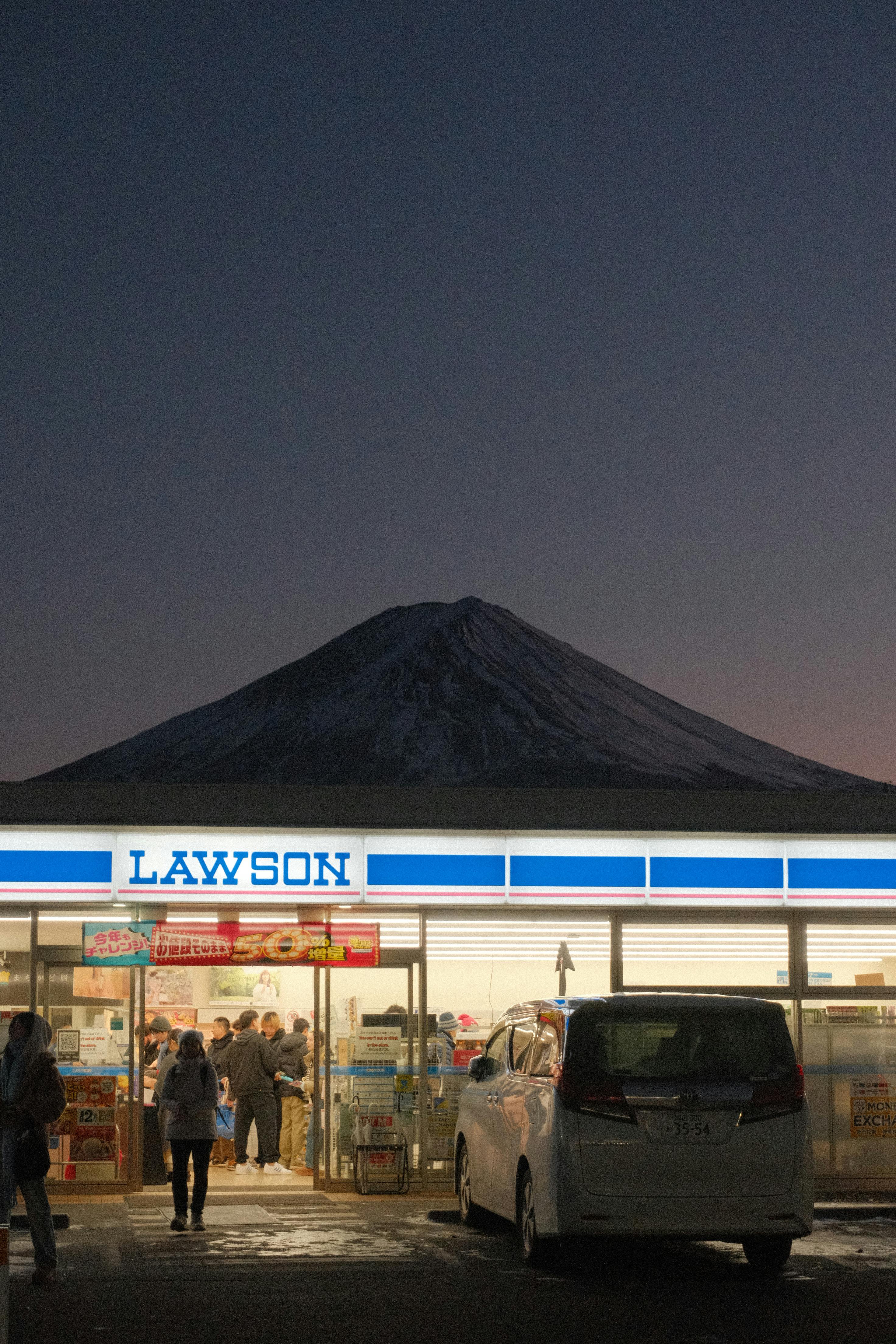 Evening scene at Lawson store with Mount Fuji in the background at dusk.