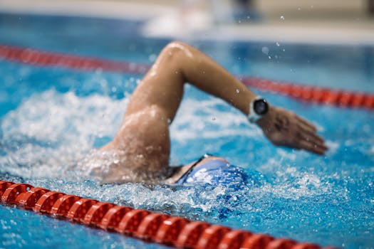 A focused swimmer performs a freestyle stroke in a competition-grade indoor pool.