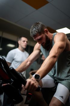 Focused men engaged in a high-intensity indoor cycling session at the gym.