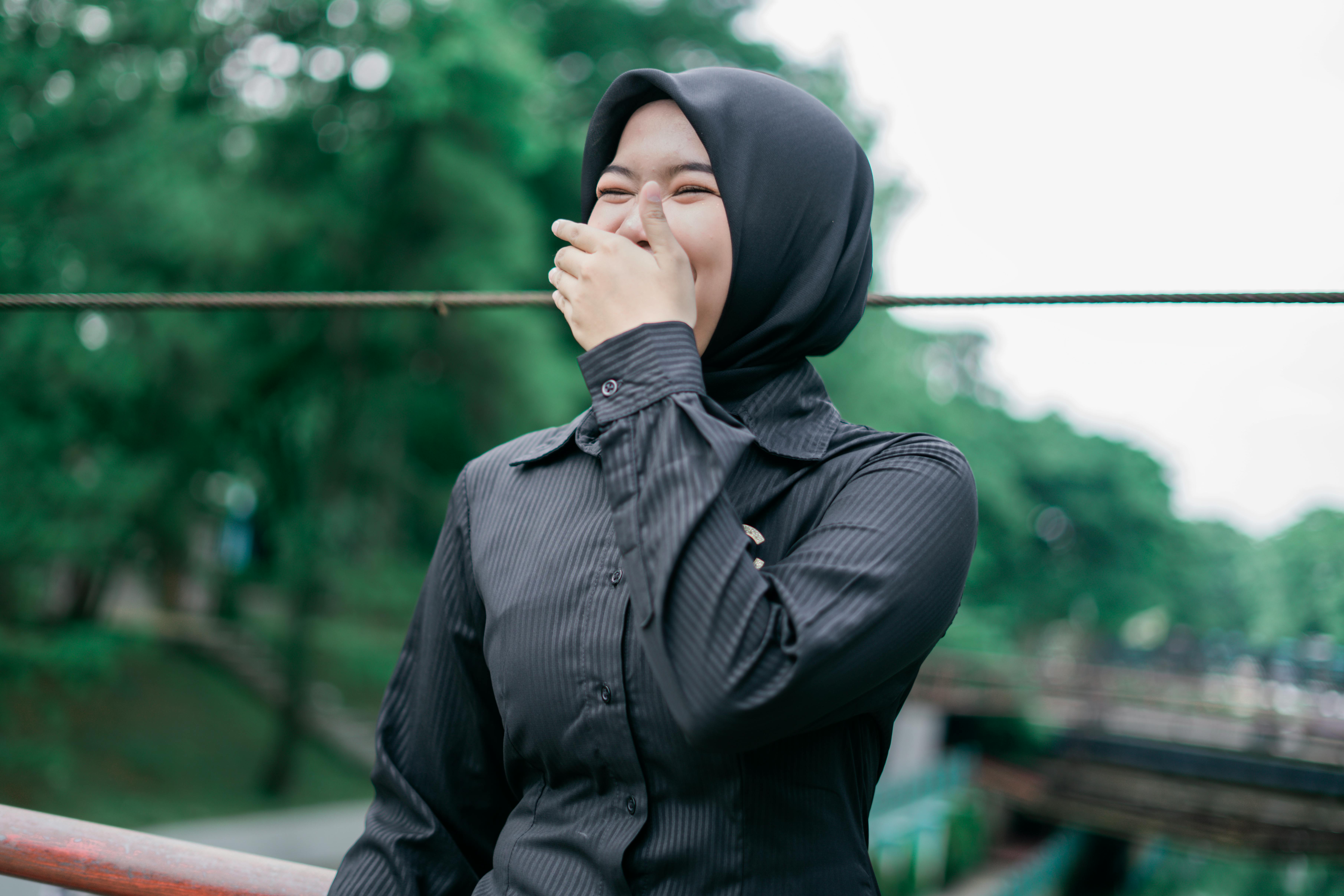 Gratis Una donna musulmana felice, con un hijab nero, ride gioiosamente all'aperto a Banten, in Indonesia. Foto a disposizione