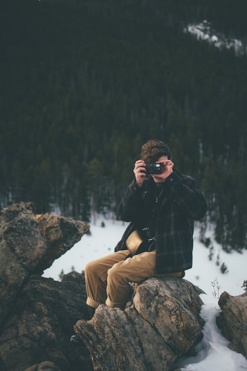 Man Met Behulp Van Camera Zittend Op Een Rots