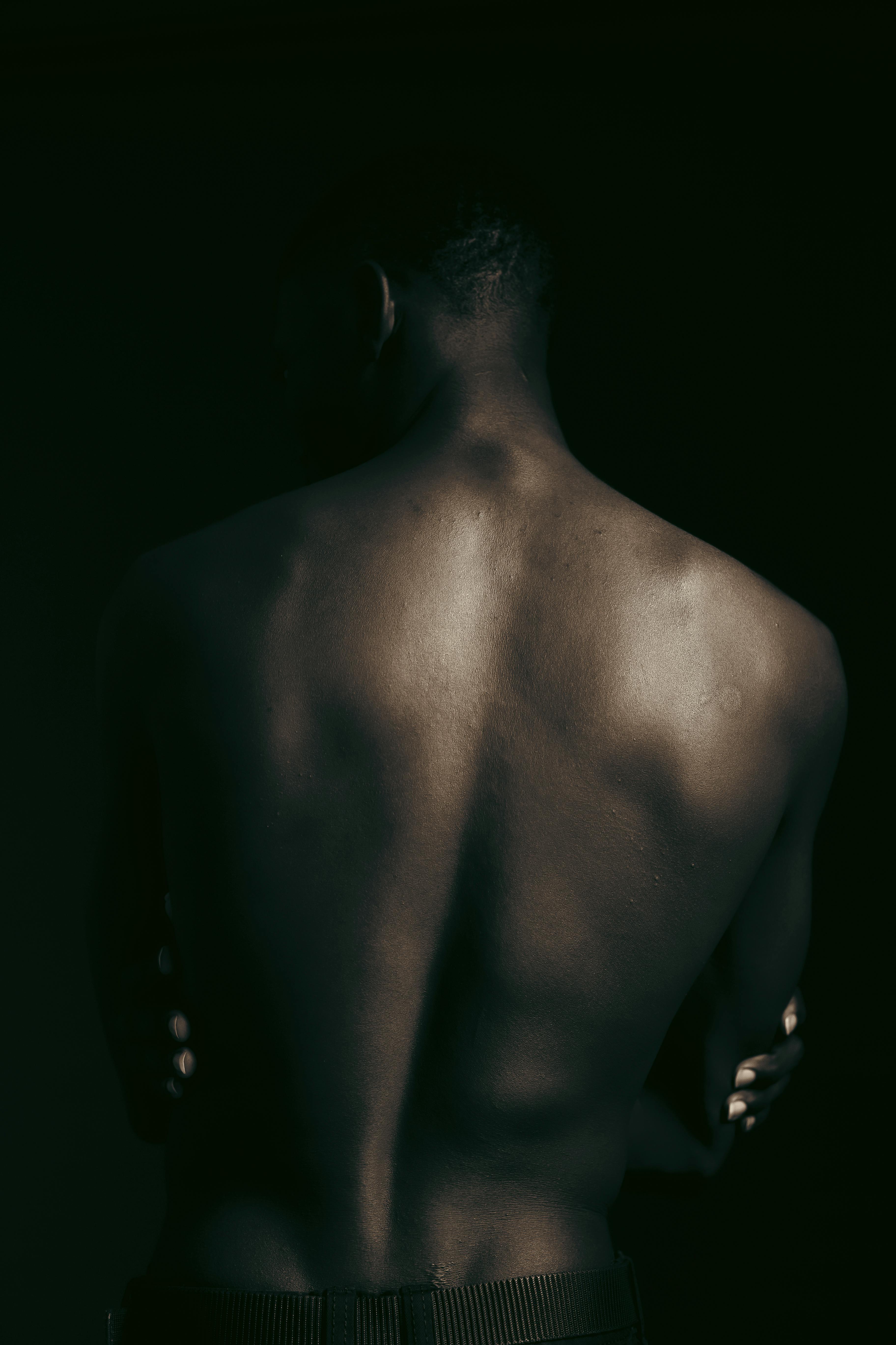 Gratis Schiena maschile in una luce soffusa e drammatica, che mette in mostra ombre e forme artistiche Foto a disposizione