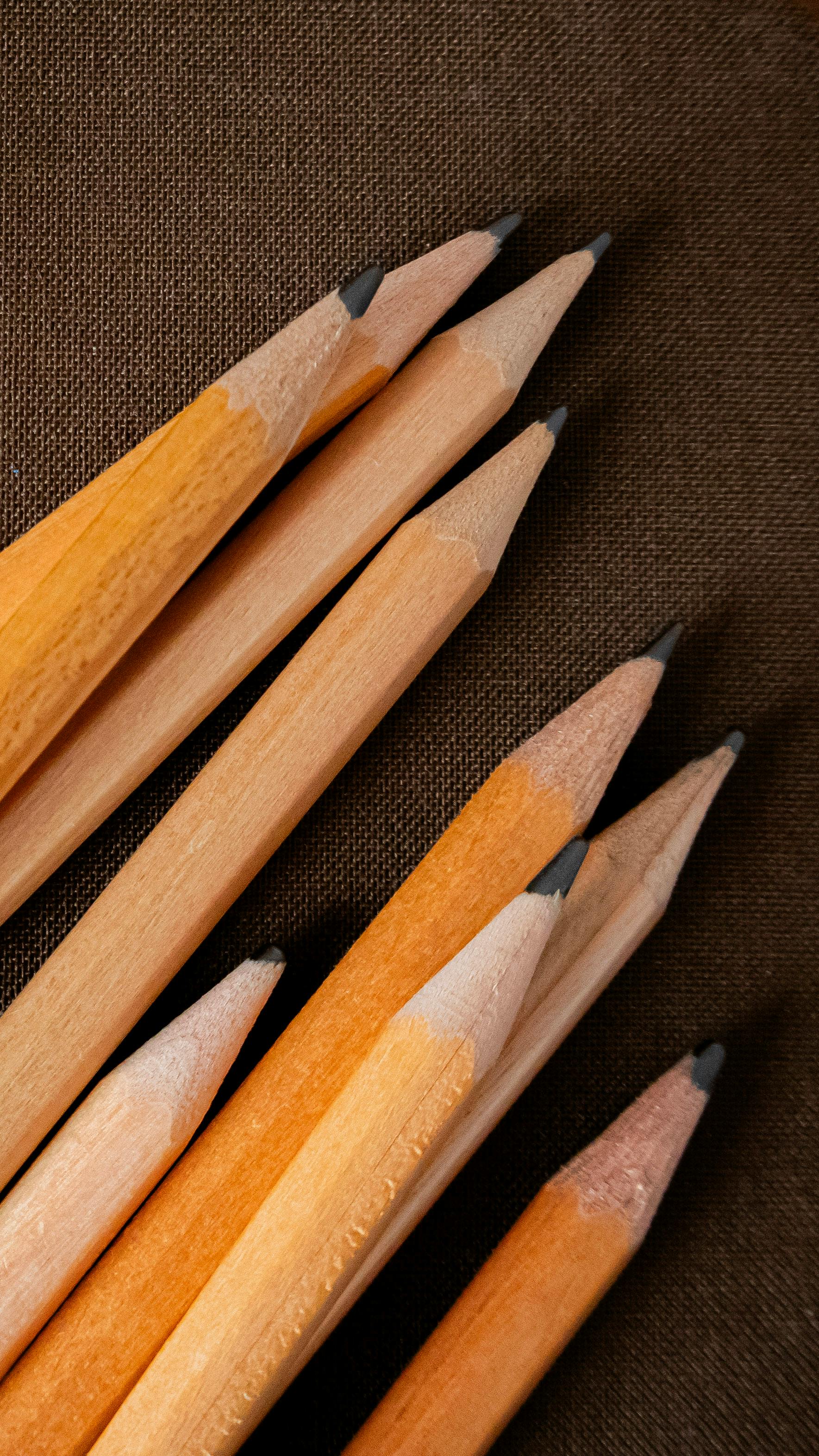 Gratis En gruppe skarpe treblyanter arrangert på teksturert stoff, perfekt for kunst og skoletemaer. Arkivbilde