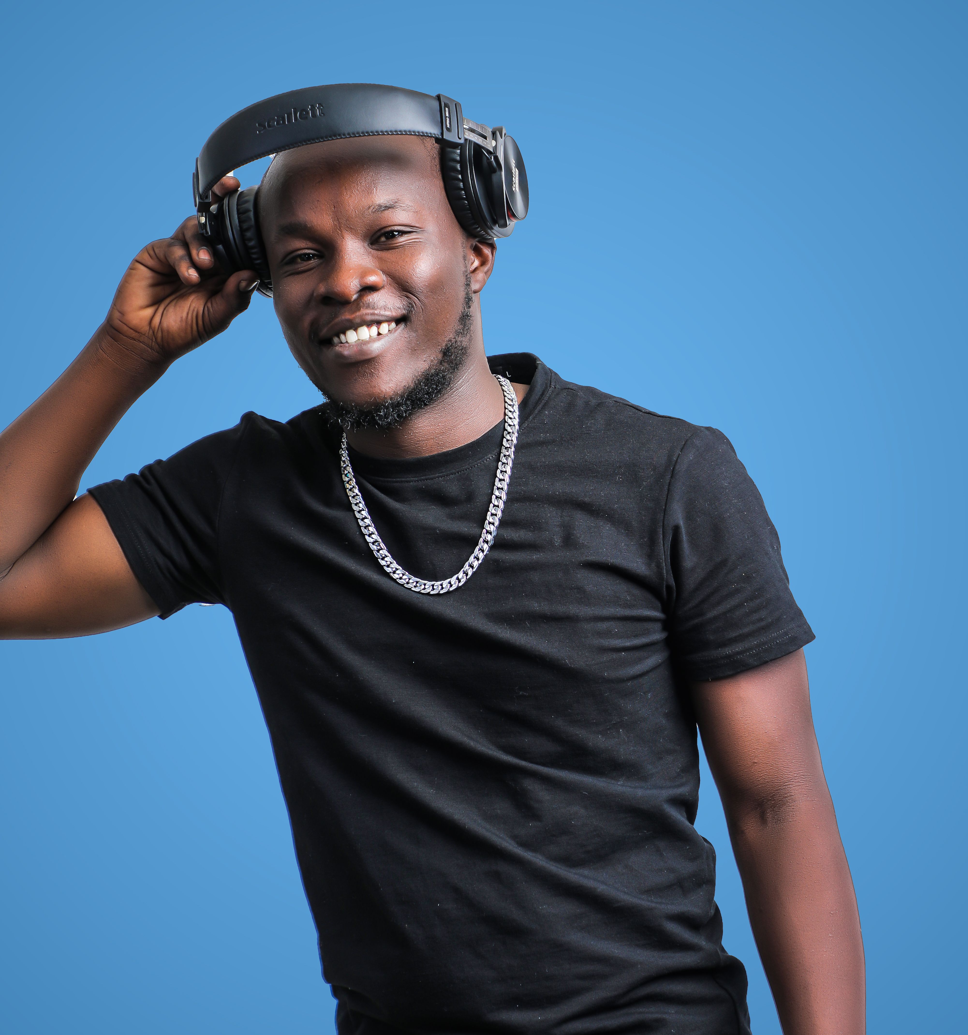 A cheerful man wearing headphones and a black shirt against a blue backdrop.