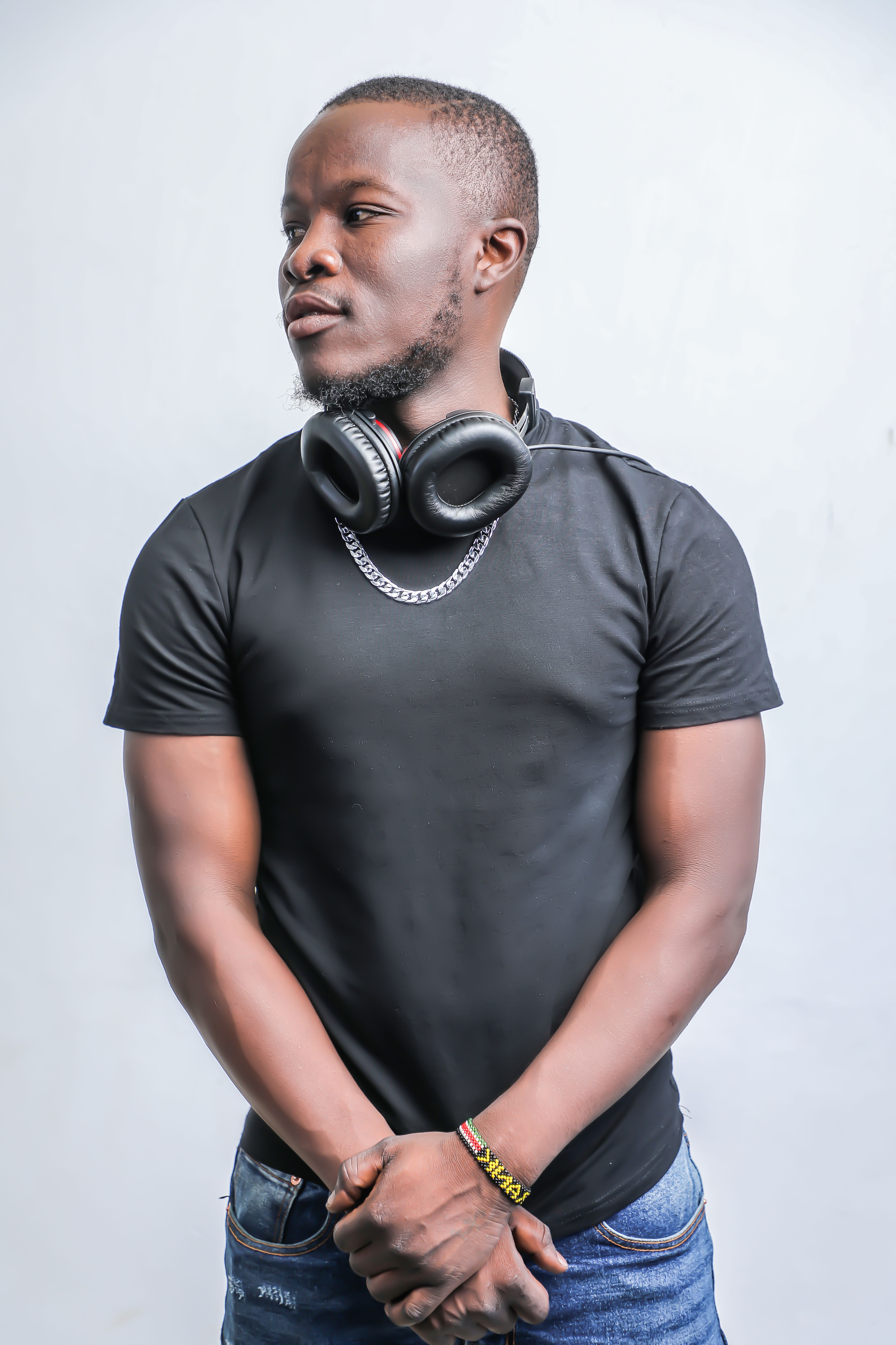 Studio portrait of a man wearing black t-shirt and headphones, looking away.