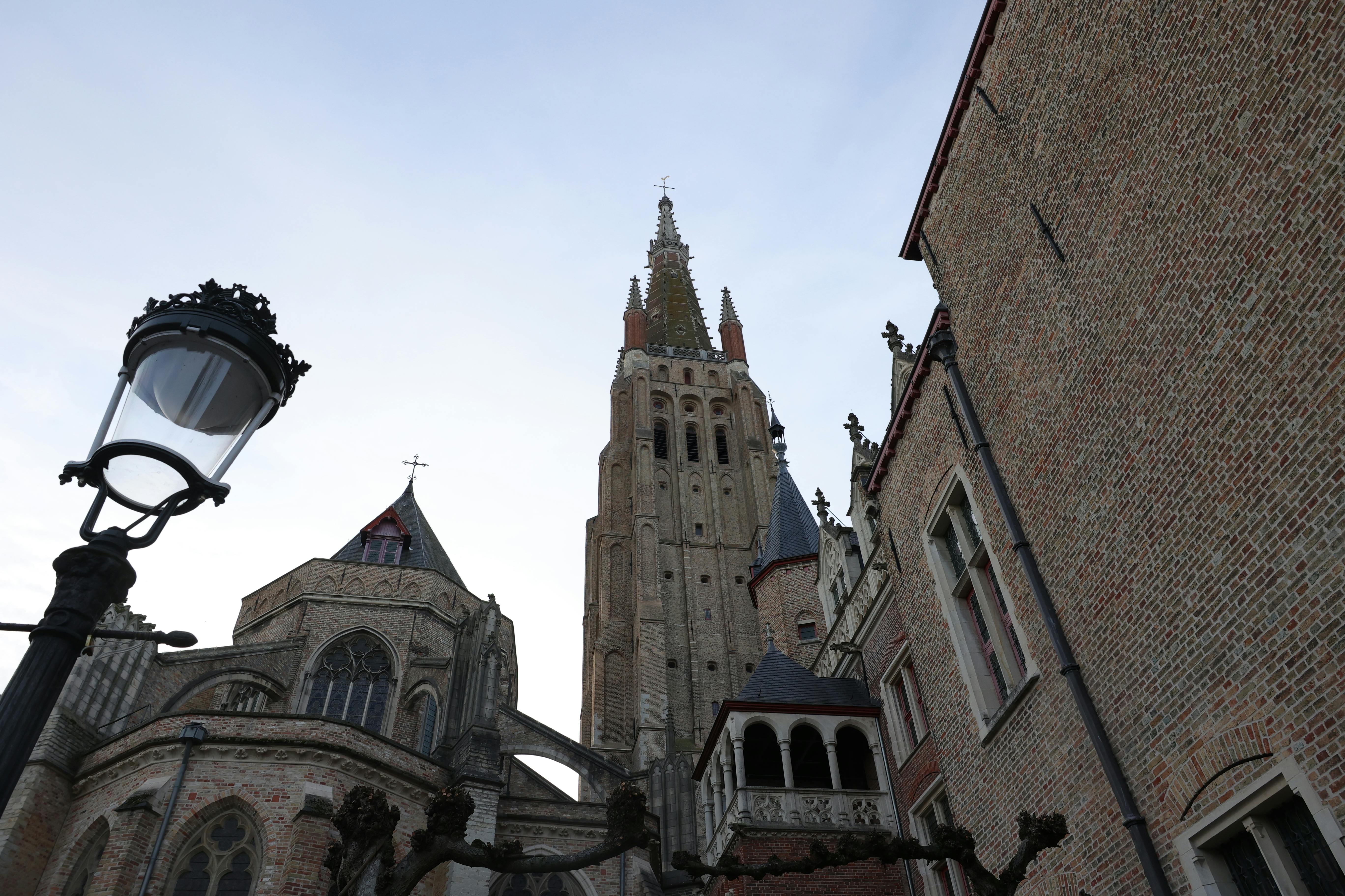 Free View of the Church of Our Lady in Bruges showcasing its Gothic architecture from a street angle. Stock Photo