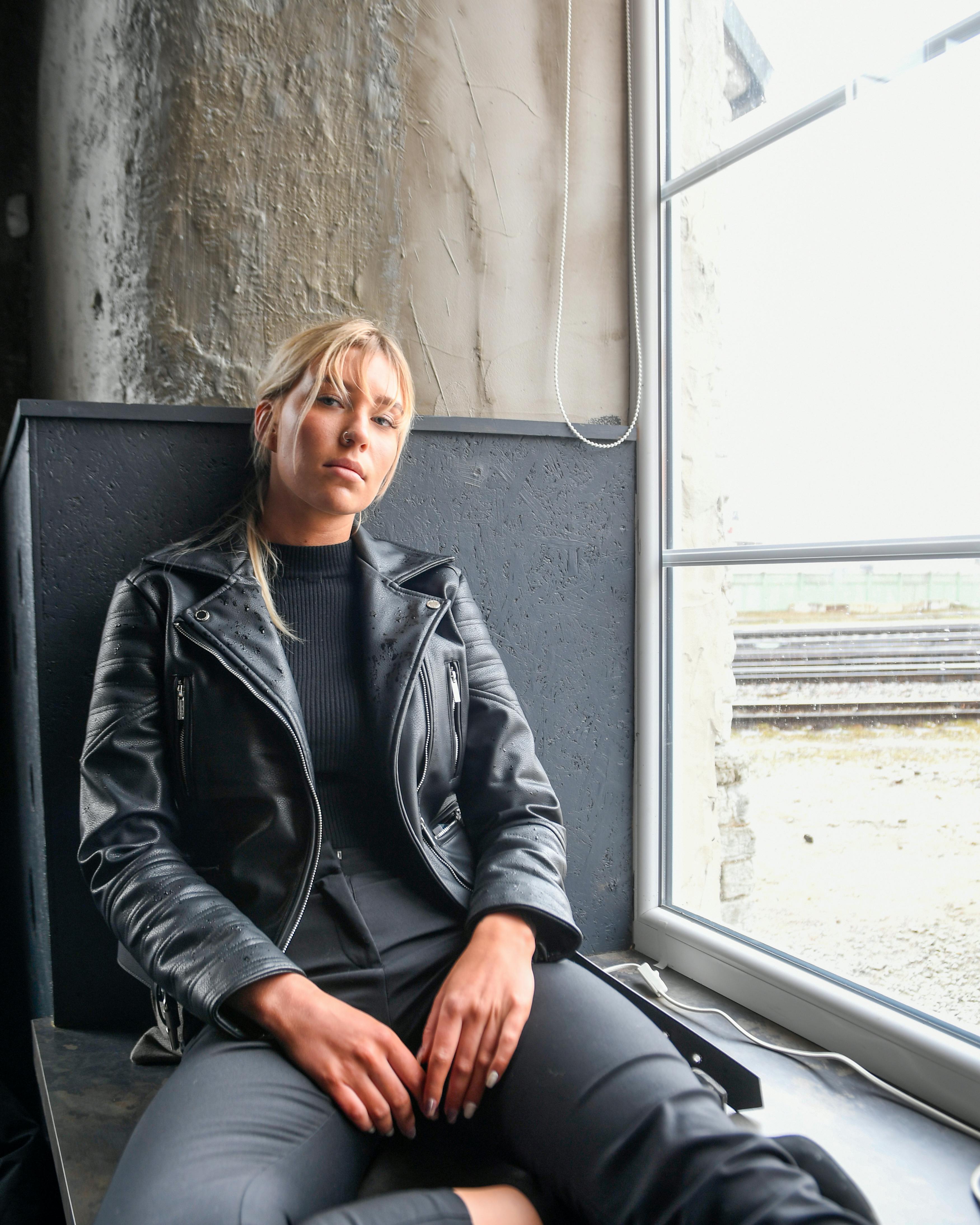Miễn phí Chân dung một người phụ nữ mặc áo khoác da ngồi bên cửa sổ ở Tallinn, Estonia. Ảnh lưu trữ