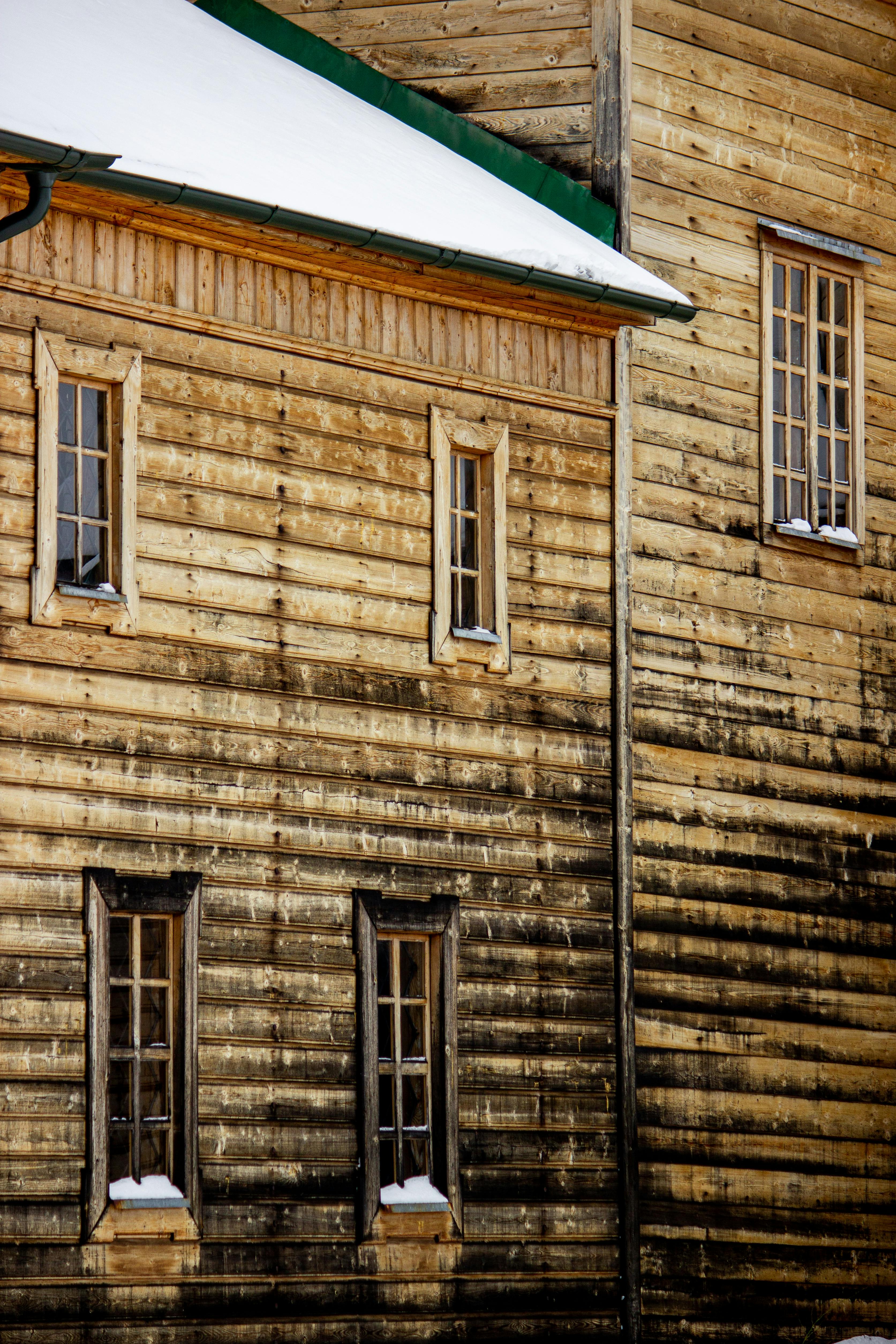 無料 屋根と窓に雪が積もった素朴な木造建築物の外観のクローズアップ。 写真素材