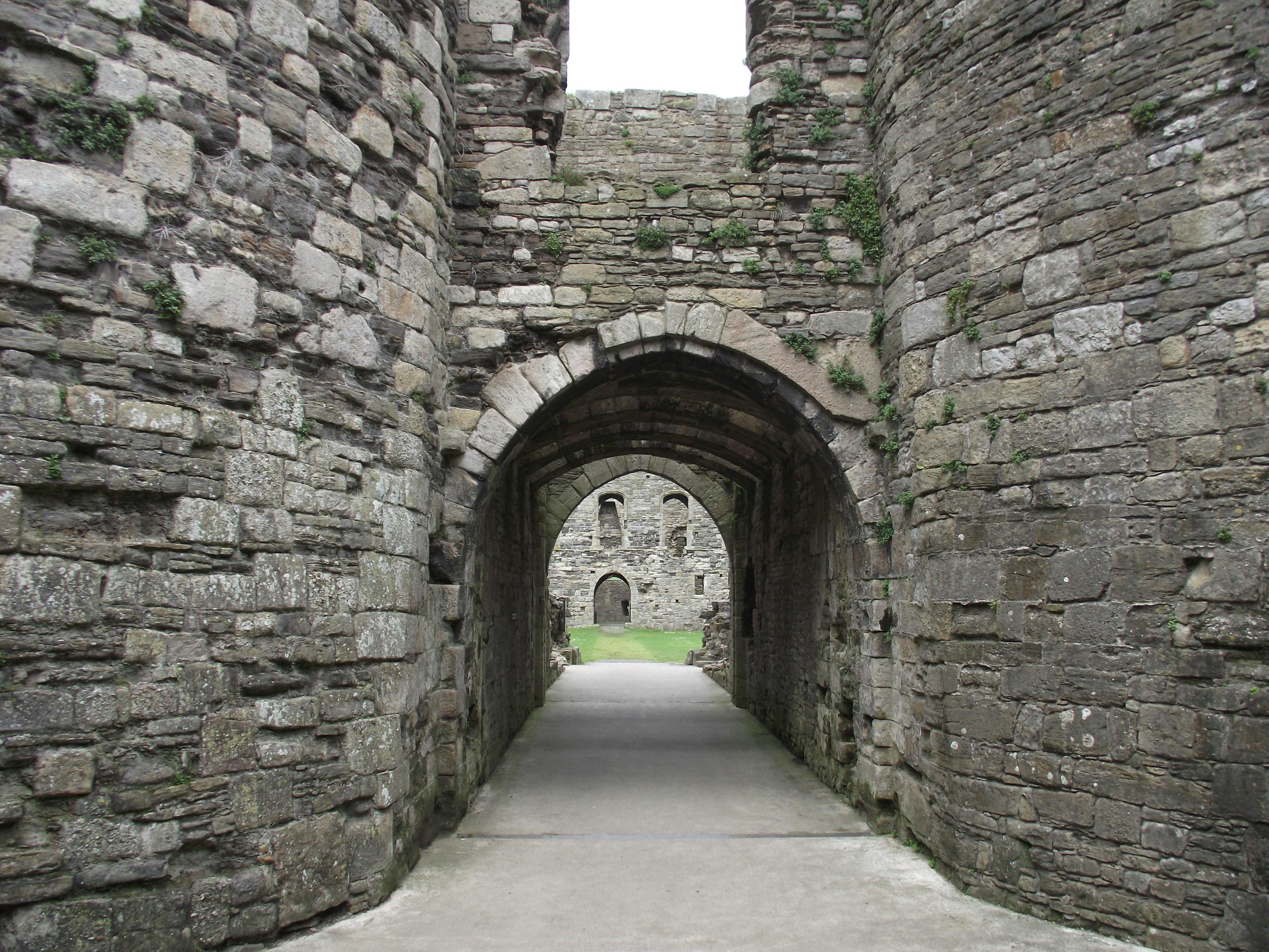 Gratis Jelajahi gapura dan koridor kastil batu abad pertengahan yang mengarah ke halaman dalam. Foto Stok