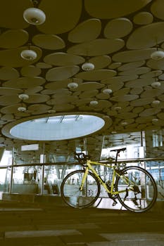 Yellow bicycle under a modern geometric ceiling in Taipei, Taiwan, showcasing contemporary architecture.
