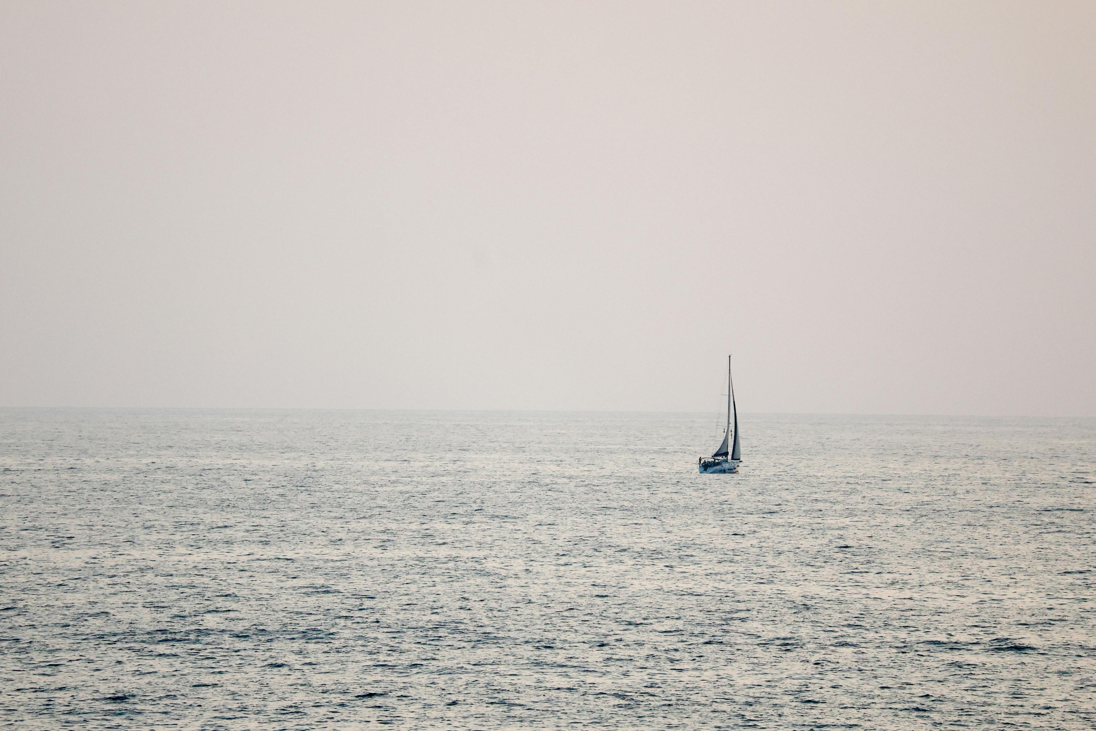 gratis Een eenzame zeilboot glijdt vredig over de uitgestrekte Middellandse Zee onder een zachte zomerhemel. Stockfoto