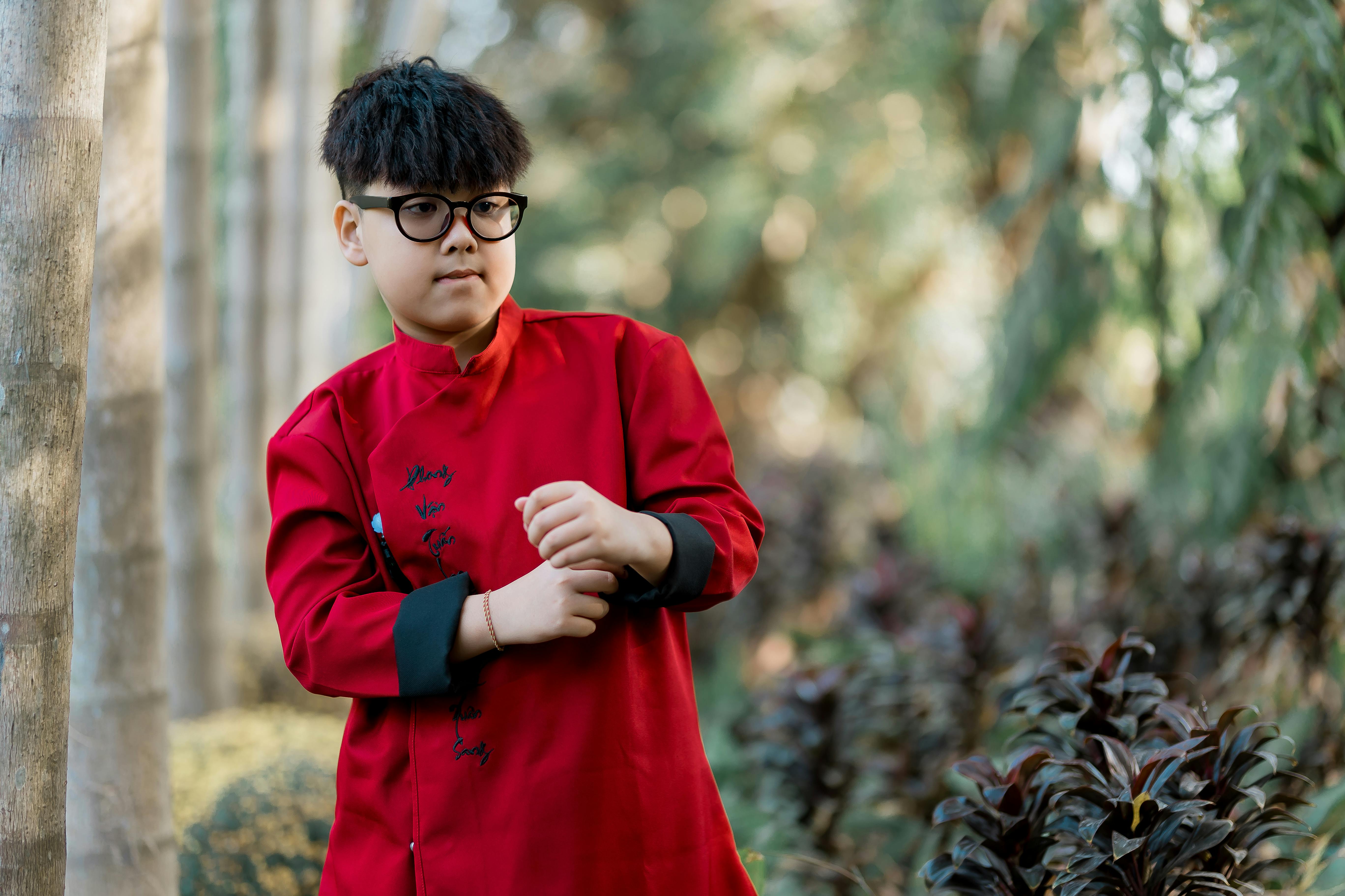 Gratis Un giovane chef in un'elegante uniforme rossa posa in un lussureggiante ambiente esterno, circondato dalla natura. Foto a disposizione