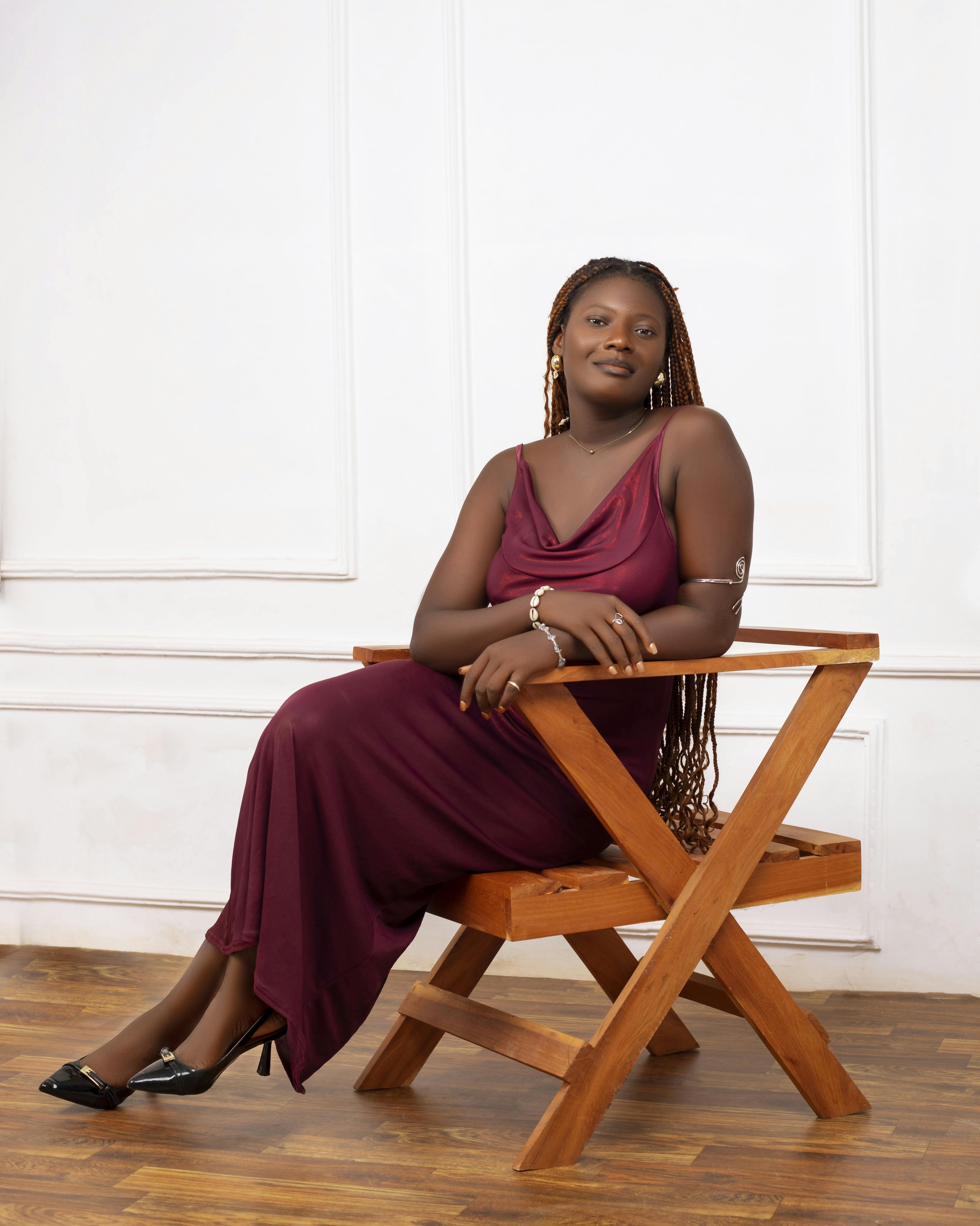 Miễn phí Chân dung một người phụ nữ thanh lịch trong chiếc váy màu đỏ sẫm đang ngồi trên chiếc ghế gỗ trong nhà. Ảnh lưu trữ