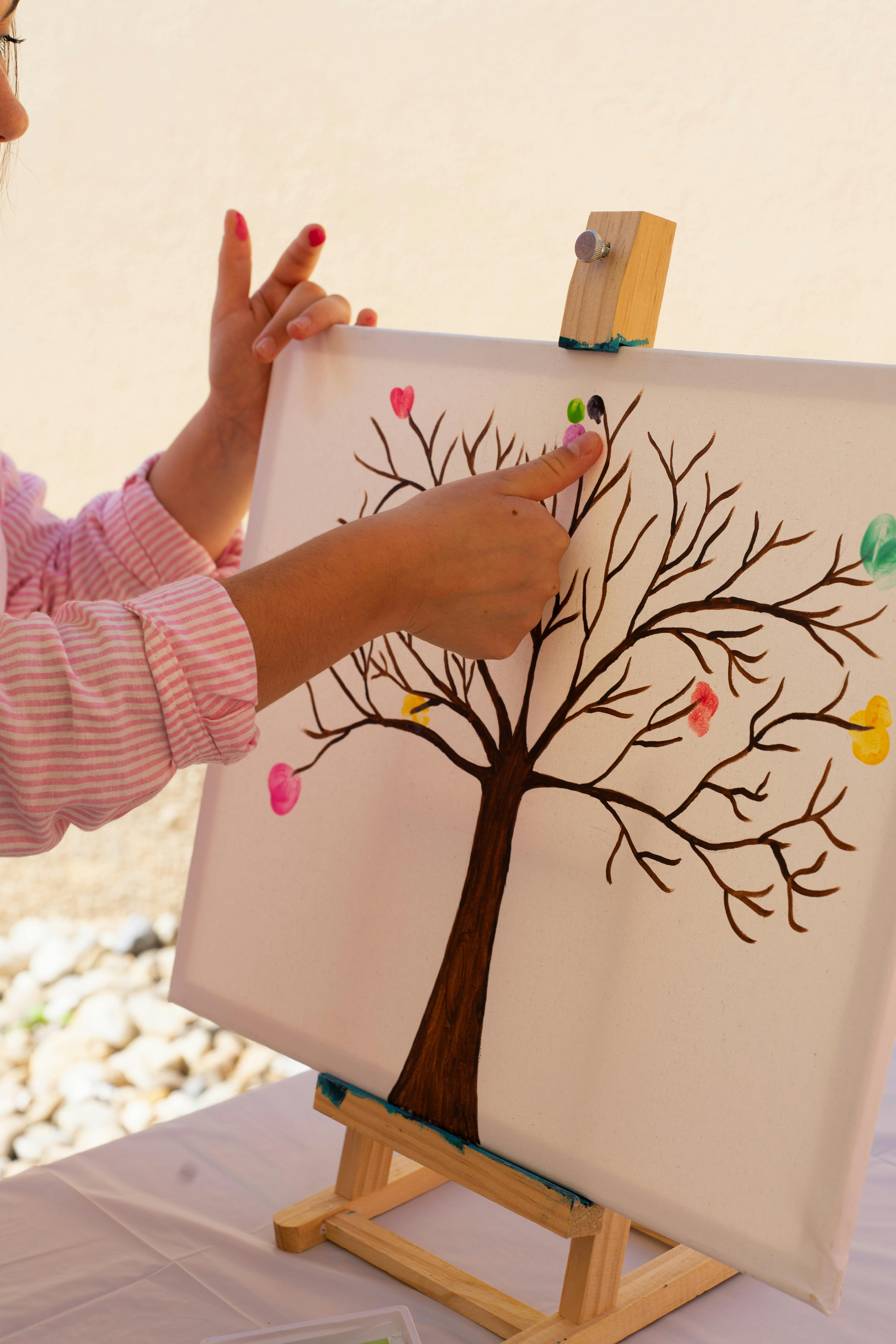 ingyenes Egy gyermek élénk, absztrakt fát alkot a szabadban ujjfestmény-technikával. Stockfotó