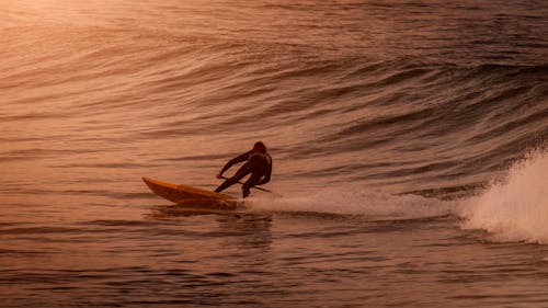 Man in Black Wet Suit Surfing on Sea