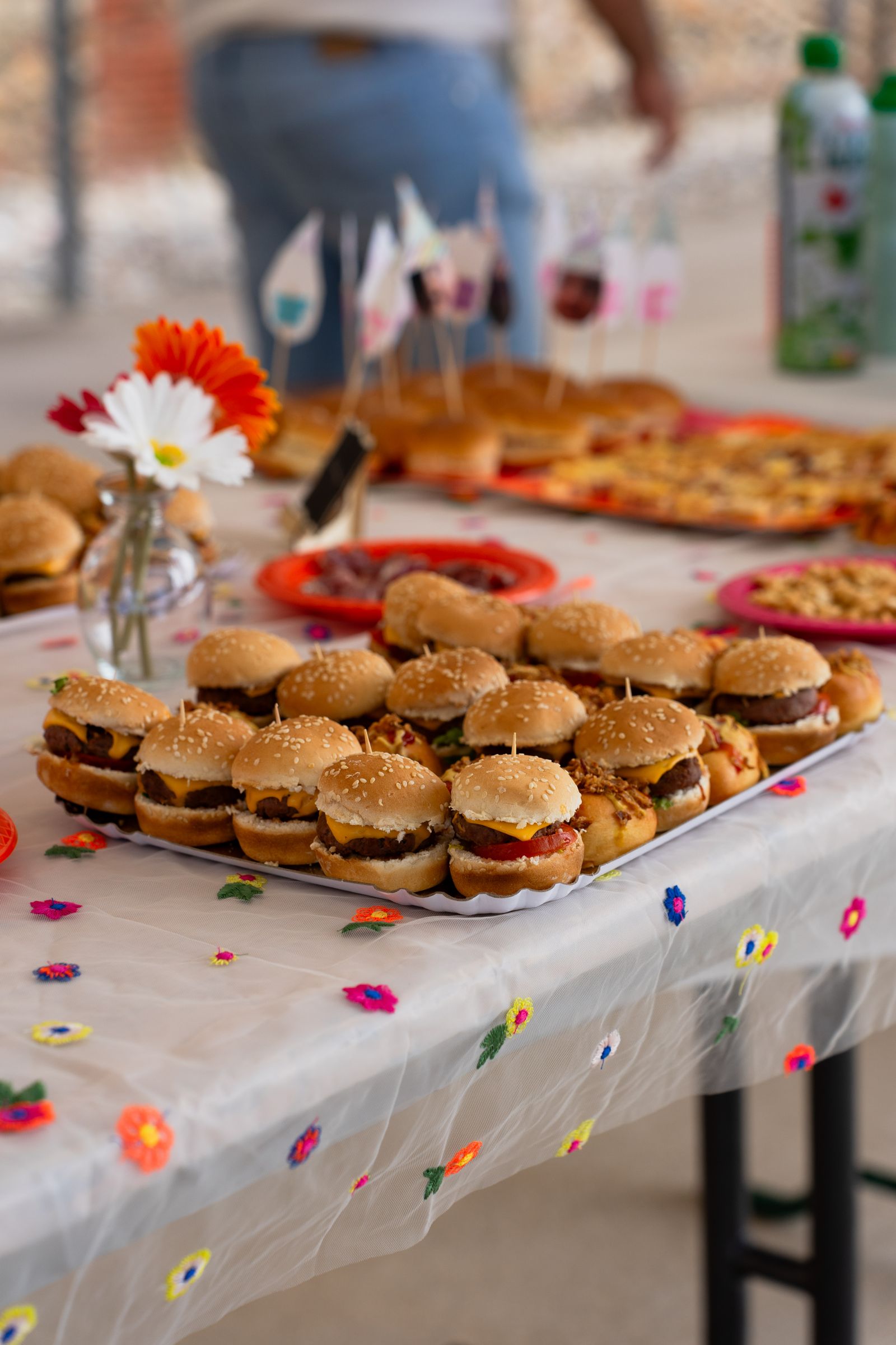 Festive buffet table with mini burgers, pizza and colourful styling