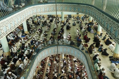Free A large congregation gathers inside an intricately designed mosque, showcasing unity during prayer. Stock Photo