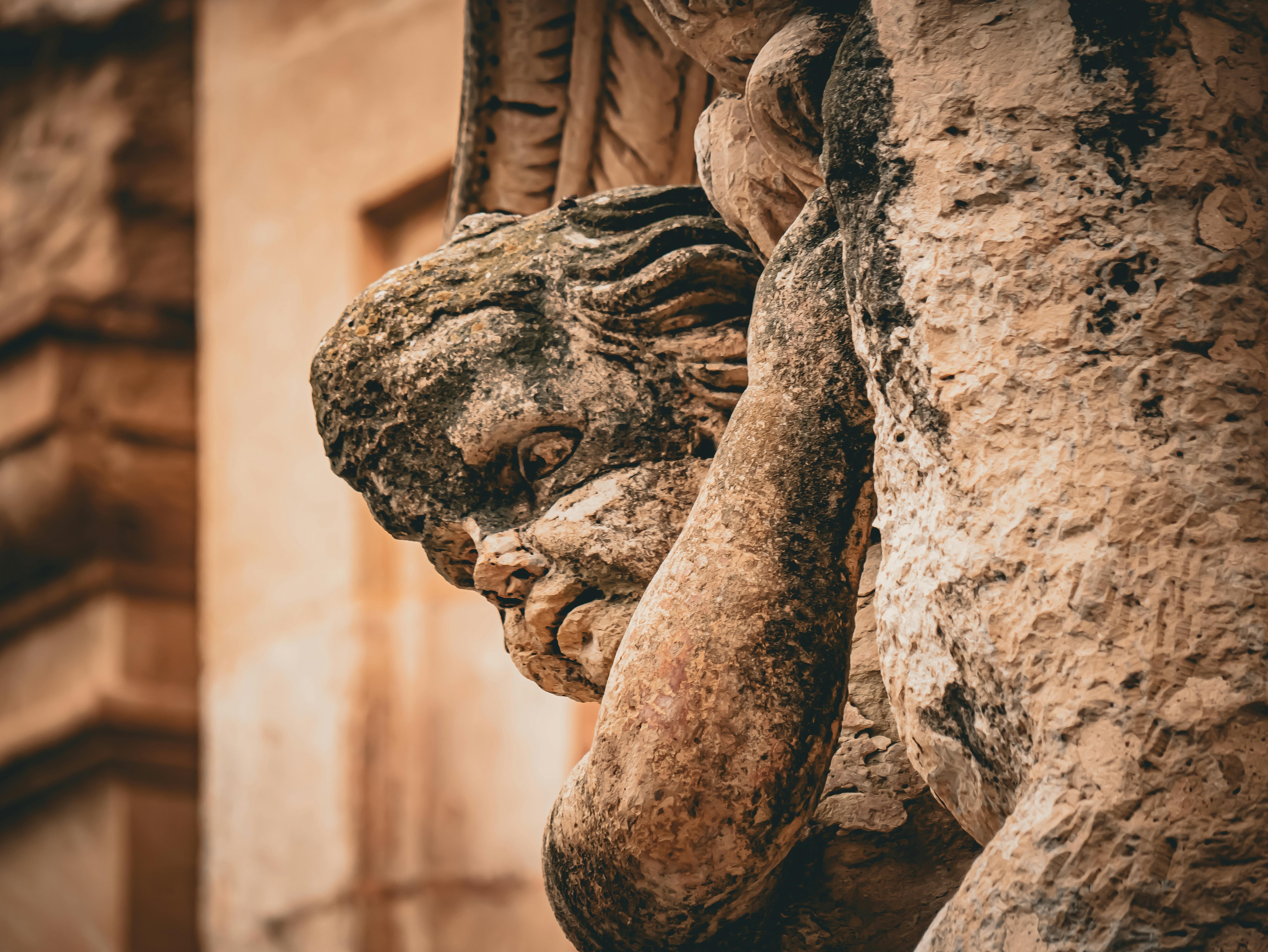 Gratis Nærbilde av en forvitret steinskulptur som forestiller en kjerub på en historisk bygningsfasade. Arkivbilde