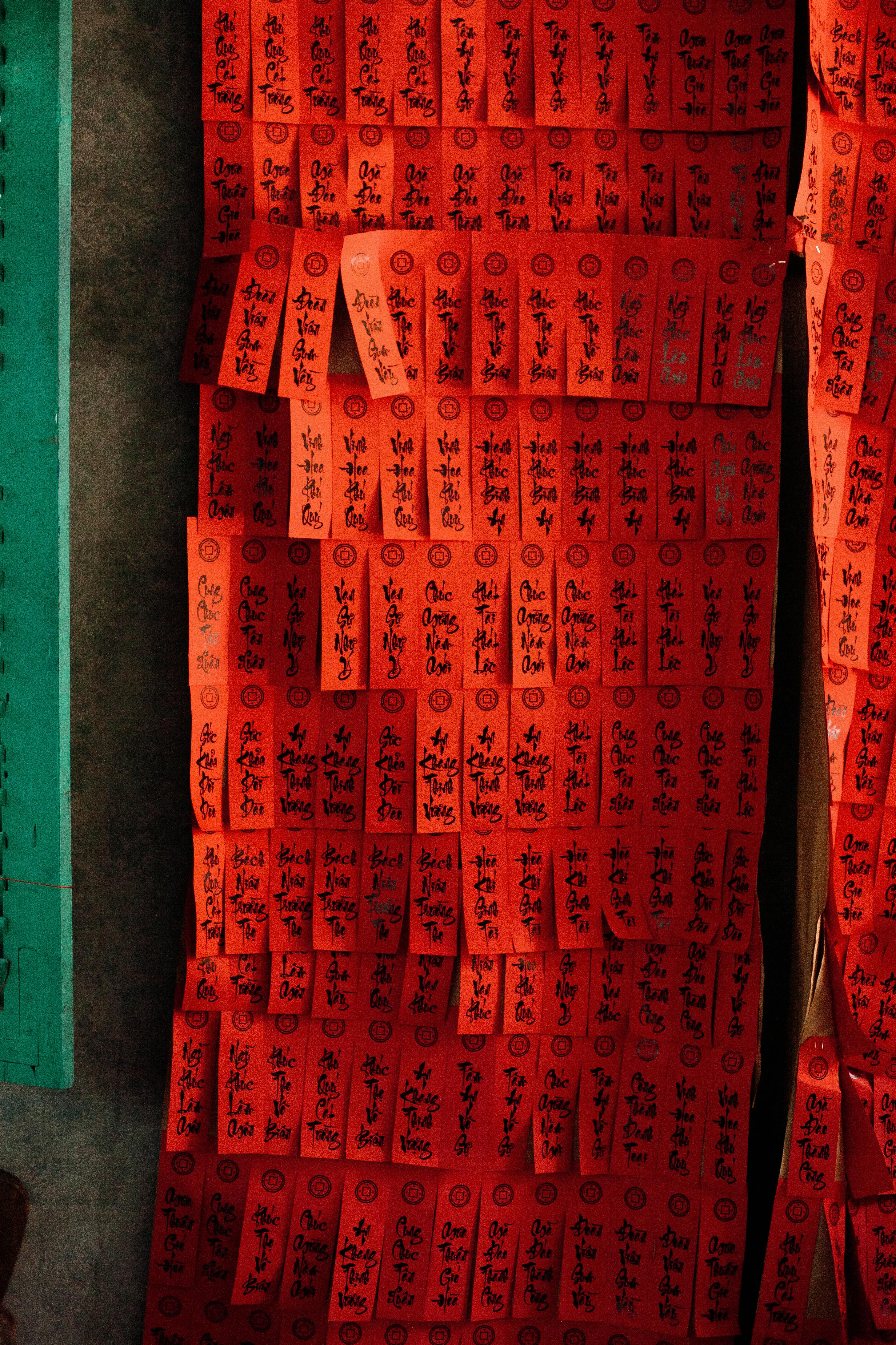 Gratis Label kertas merah bertuliskan aksara Cina tergantung di dinding, menciptakan suasana budaya dan spiritual. Foto Stok