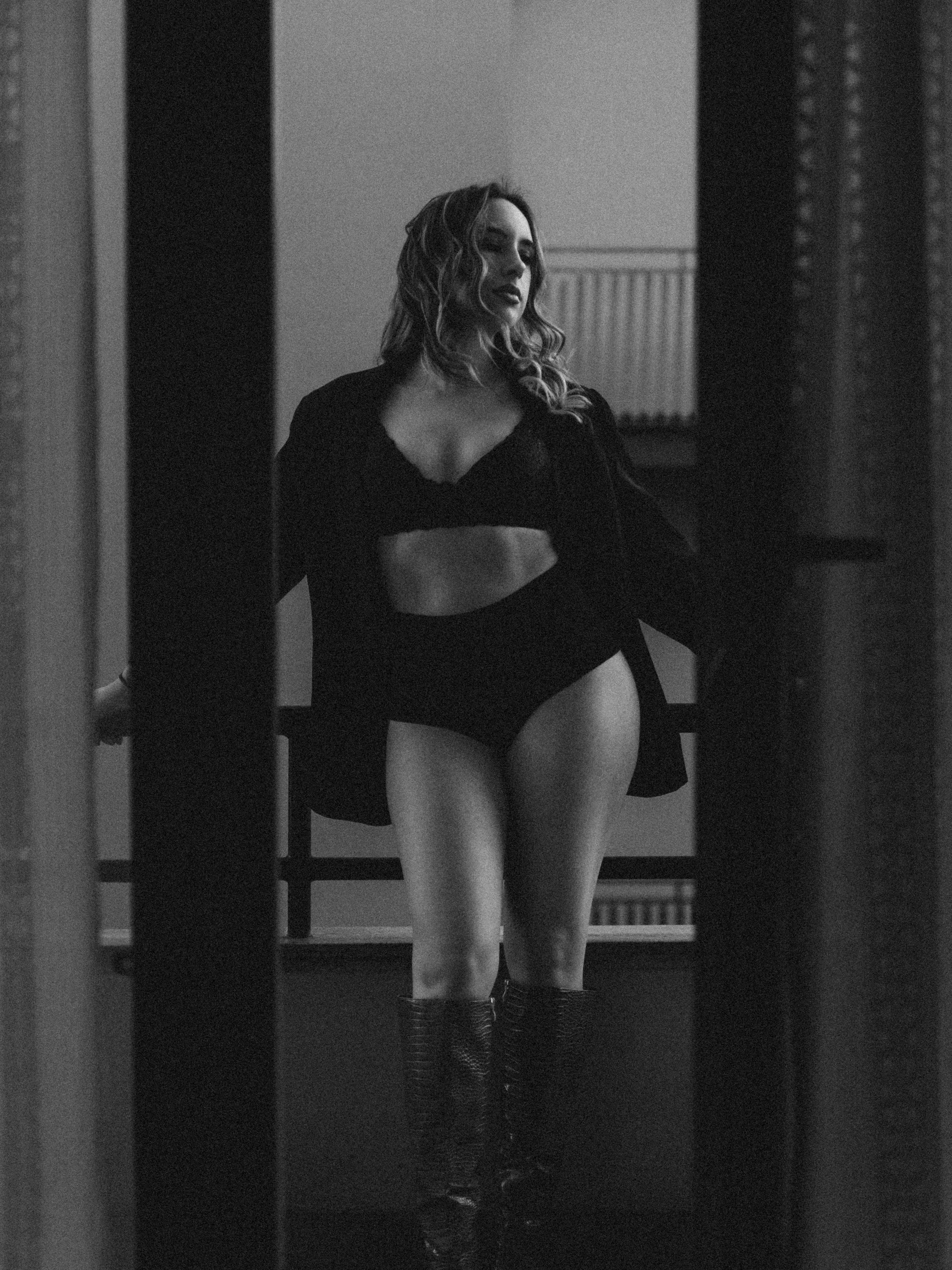 Gratis Elegant svart-hvitt-portrett av en stilig kvinne på en balkong, som utstråler selvtillit. Arkivbilde