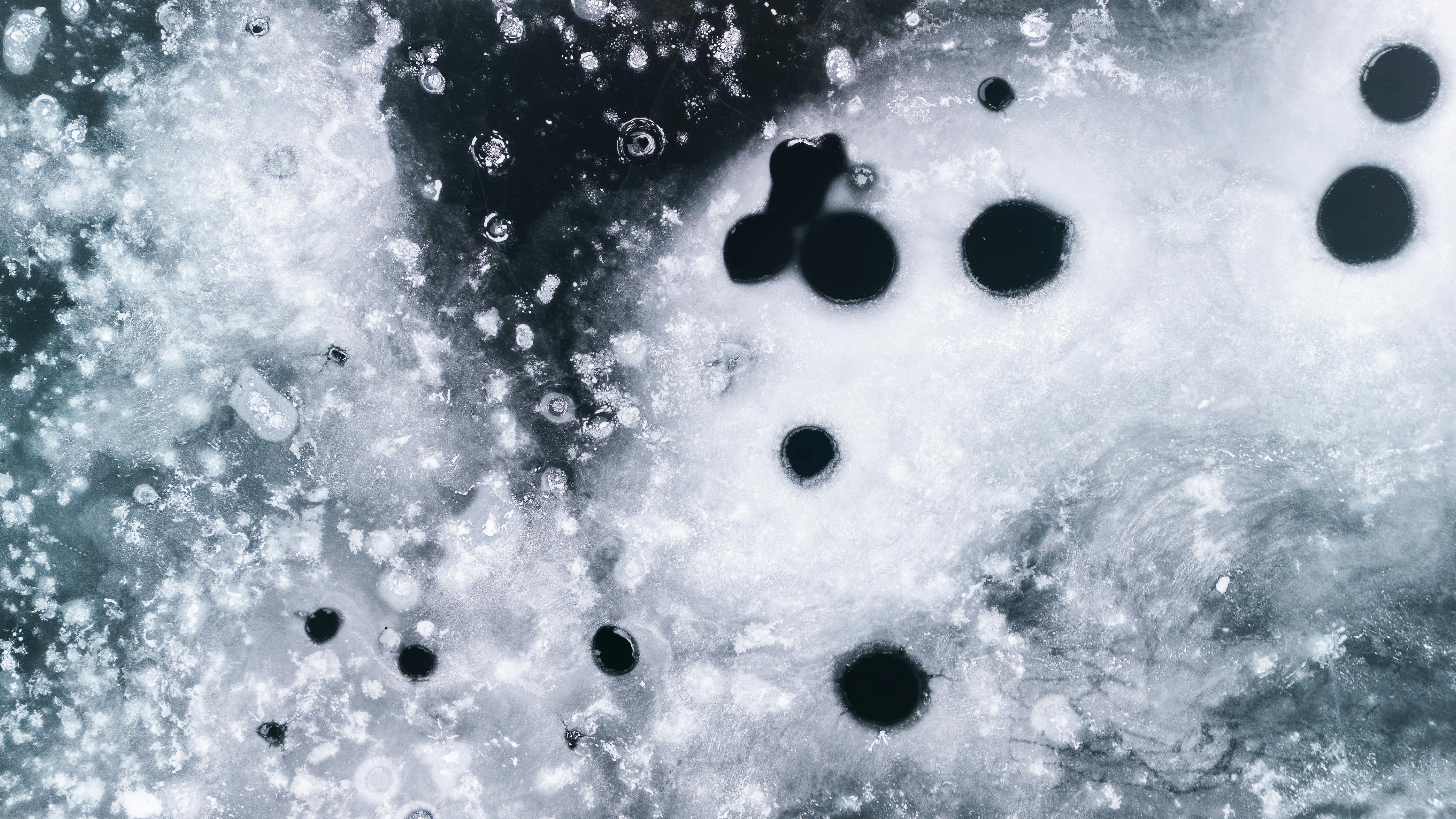 Kostnadsfria Närbild av en texturerad frusen isyta med svarta cirkulära formationer som skapar abstrakta mönster. Stock foto