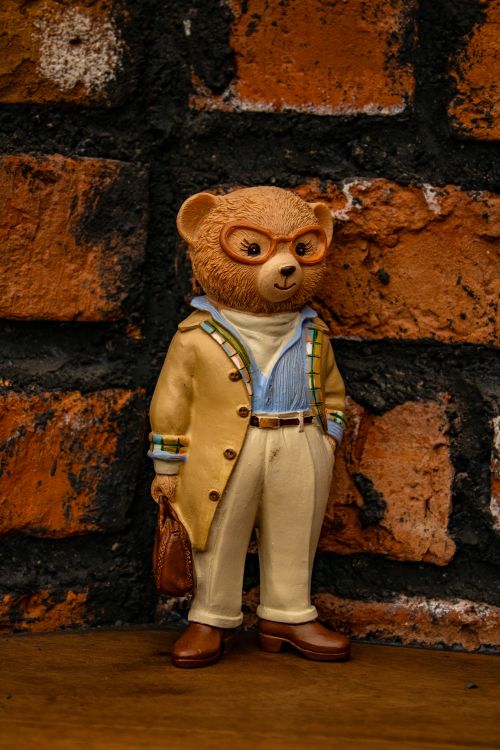 Free A fashionable teddy bear figurine in glasses posed in front of a rustic brick wall. Stock Photo