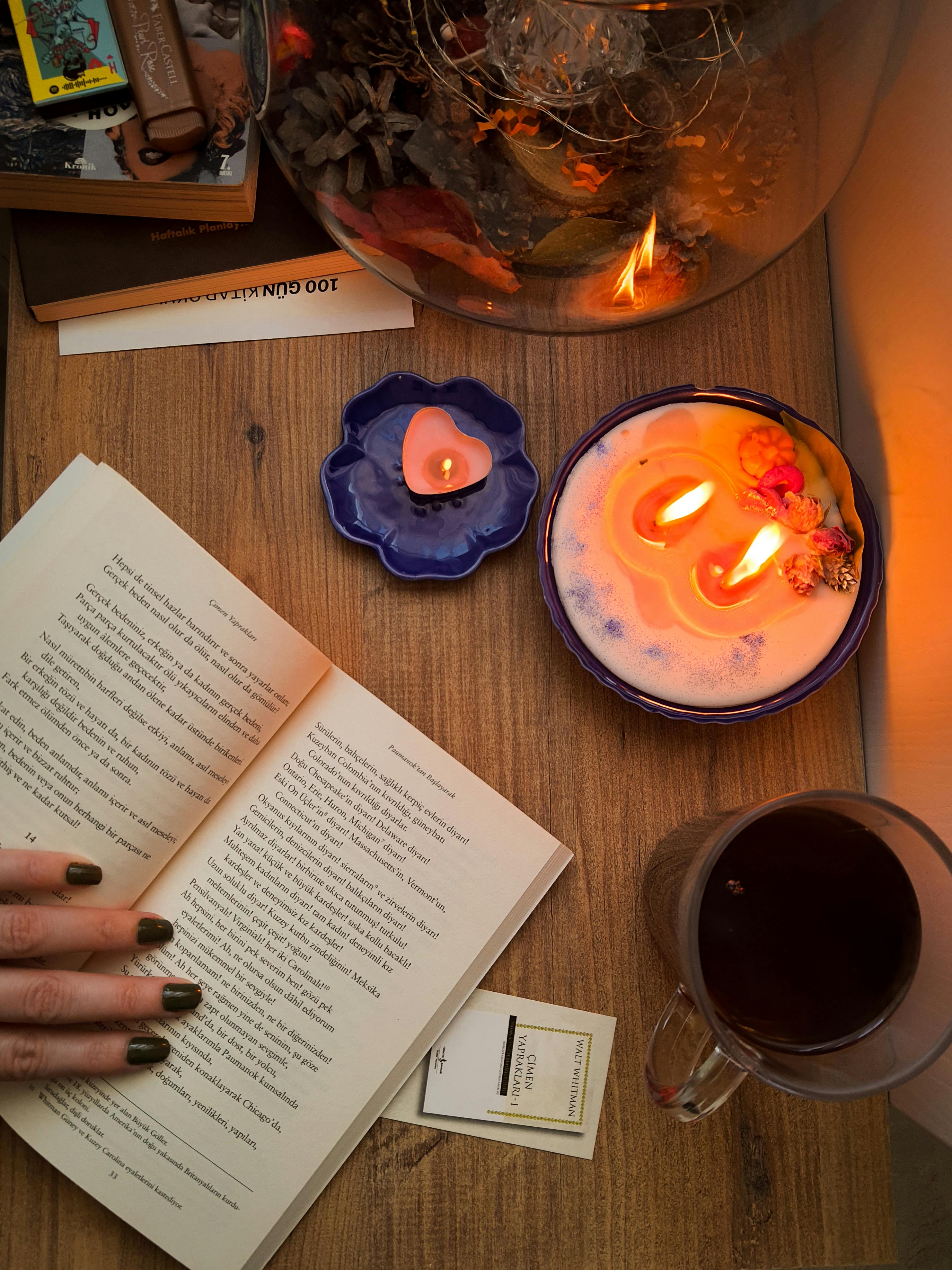 Gratis Un entorno tranquilo con un libro, velas encendidas y una taza de té en una mesa de madera. Foto de stock
