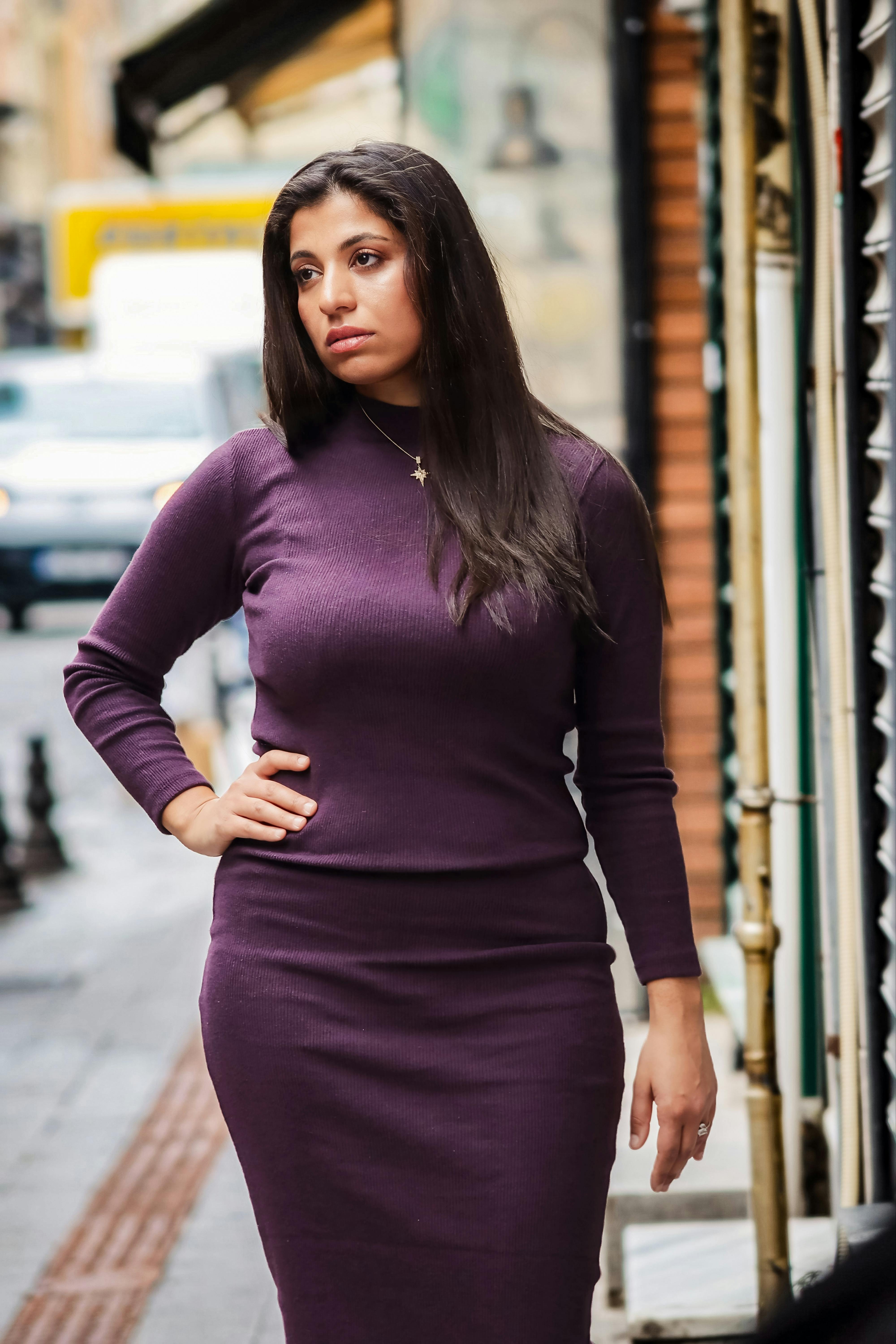 Gratis Donna con un abito viola che cammina lungo una strada cittadina, sfoggiando uno stile di moda urbano. Foto a disposizione