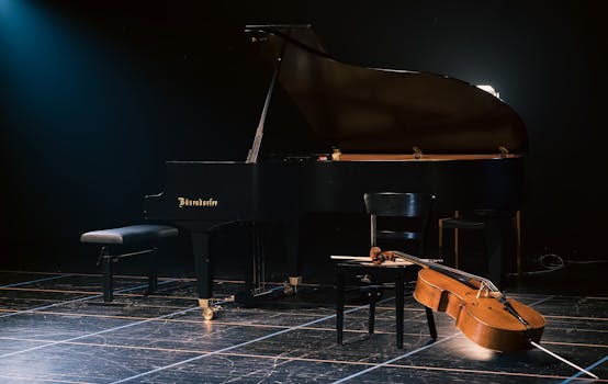 A grand piano and cello beautifully arranged on a dimly lit stage, capturing a serene musical moment.