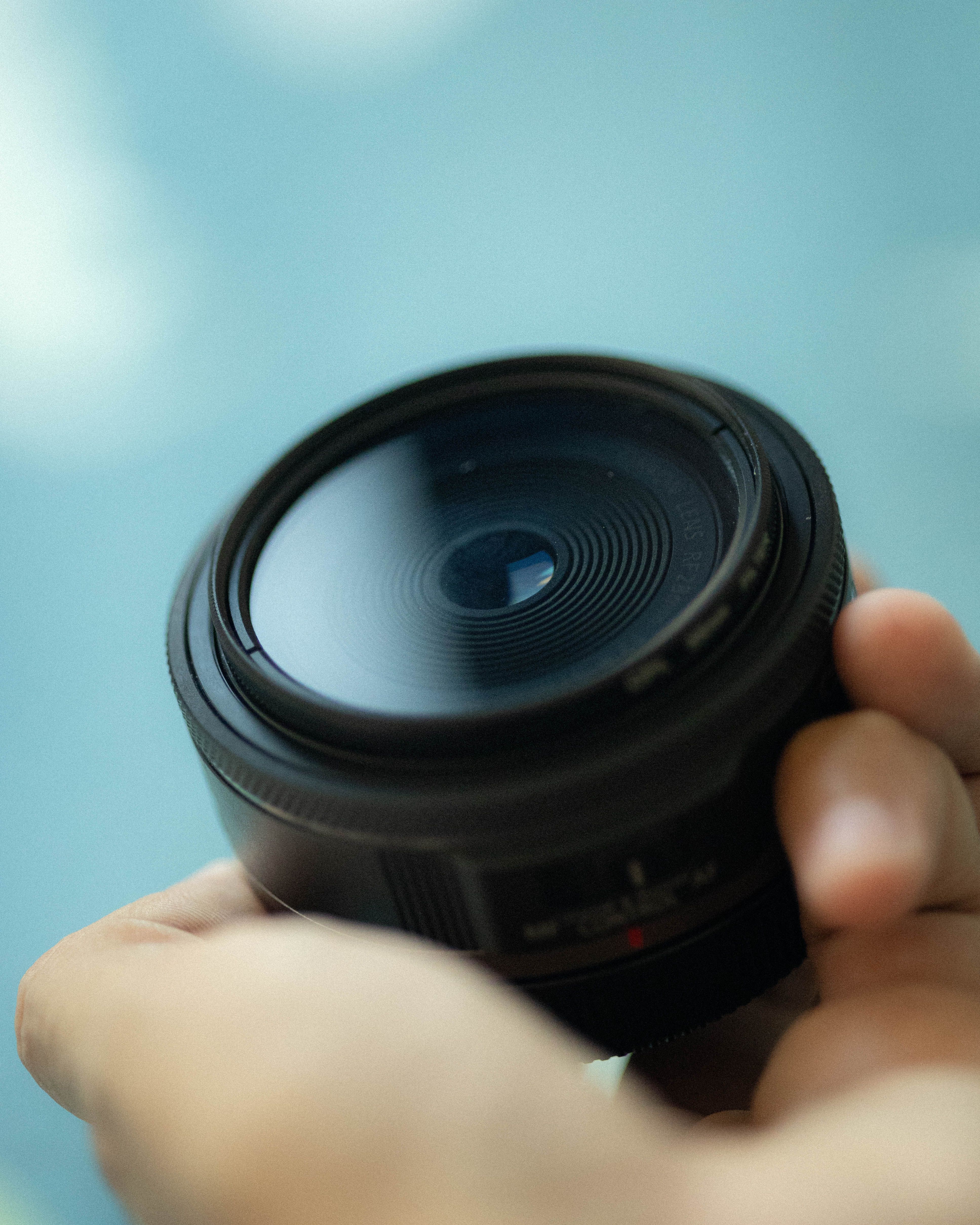 A detailed shot of a camera lens held in hands, showcasing photography gear.