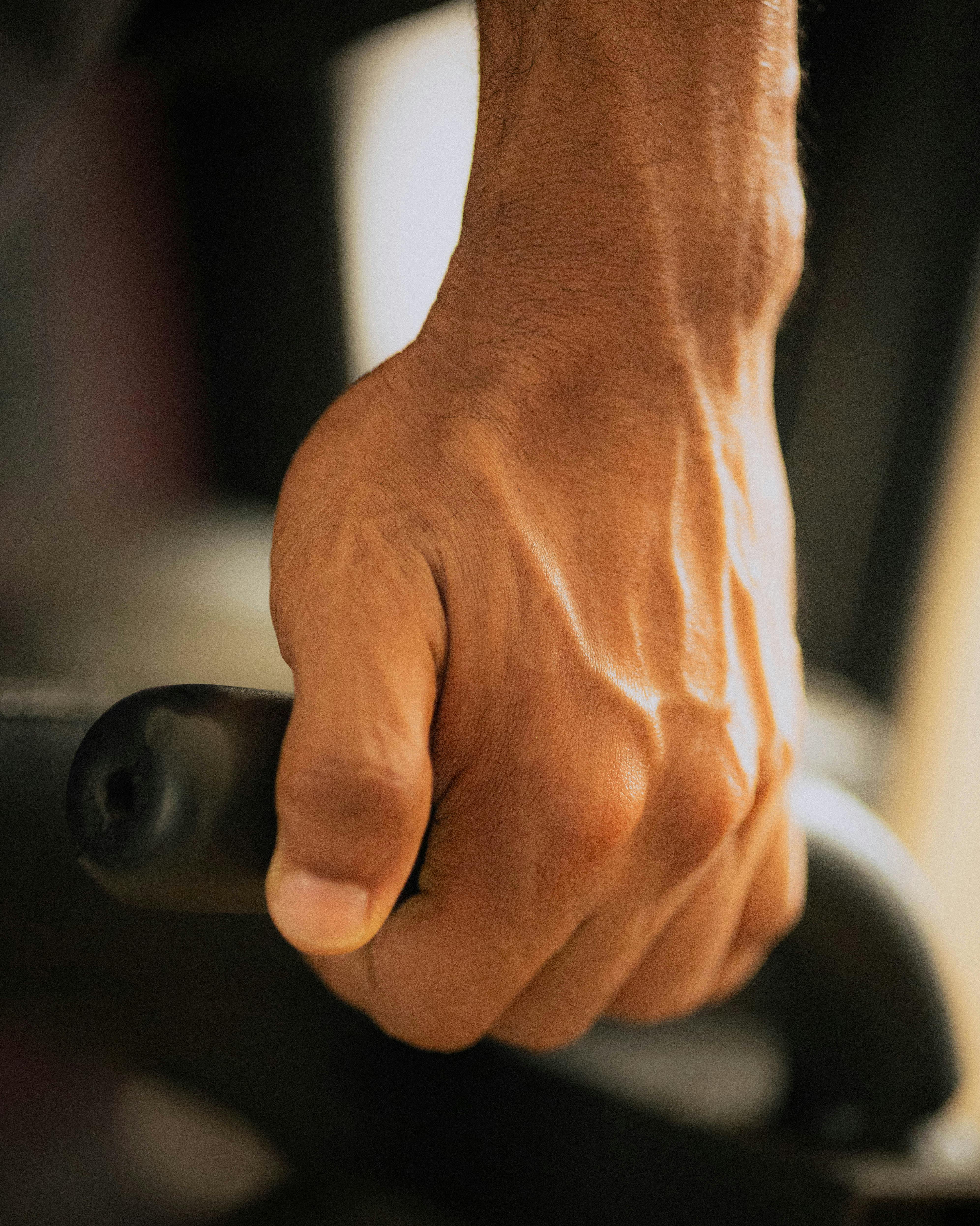 gratis Gedetailleerde close-up van een gespierde hand die fitnessapparatuur vastgrijpt, waarmee kracht en focus op fitness worden getoond. Stockfoto