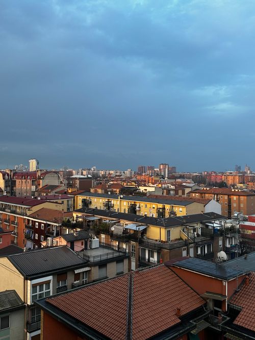 Free Panoramic view of urban rooftops under a blue sky during dusk, showcasing colorful residential architecture. Stock Photo
