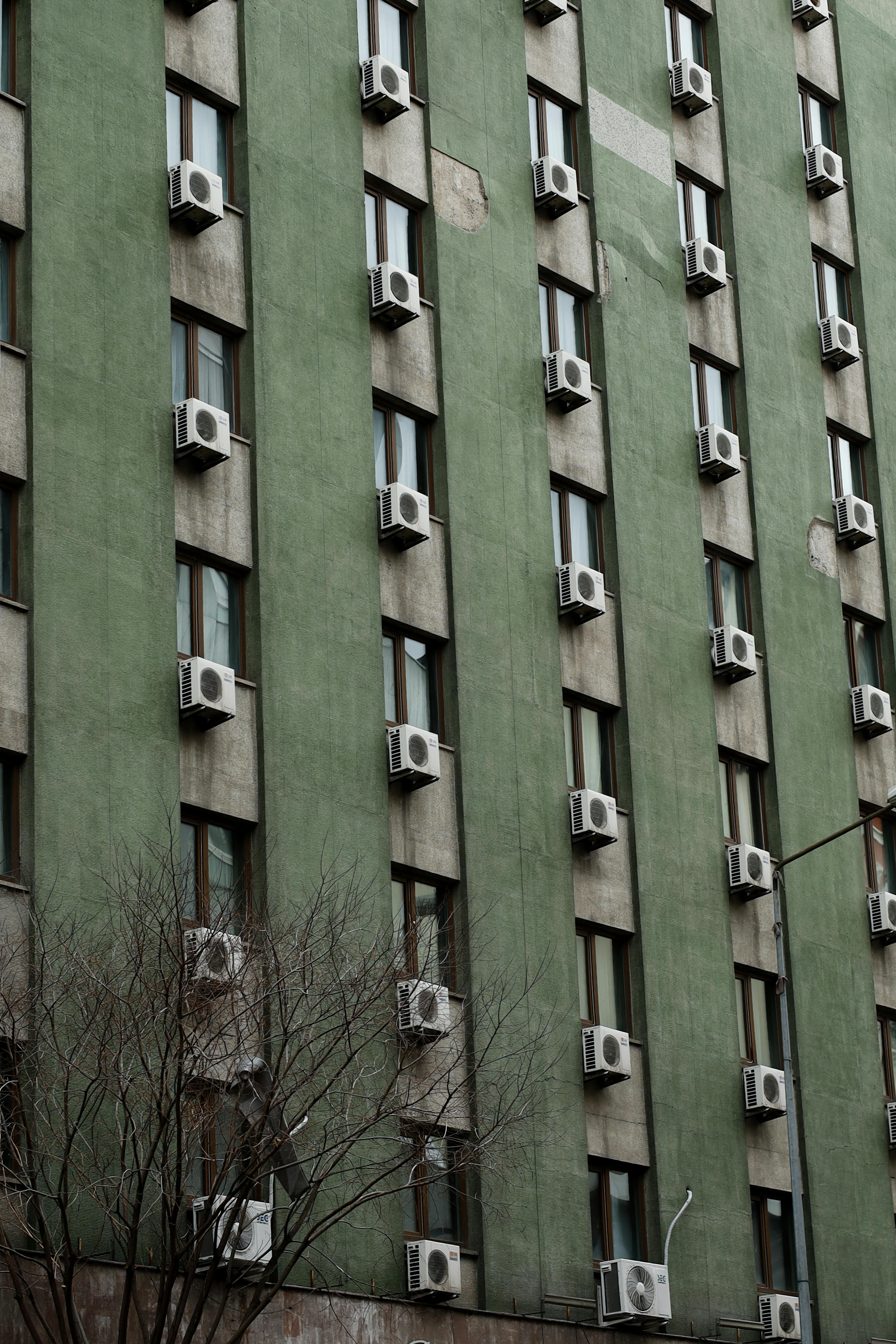 gratis Een gebouw met een groene gevel en rijen airconditioners, in een stedelijke omgeving. Stockfoto