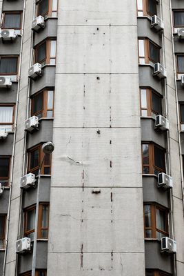 High-rise commercial building facade with multiple rooftop and wall-mounted HVAC air conditioning units
