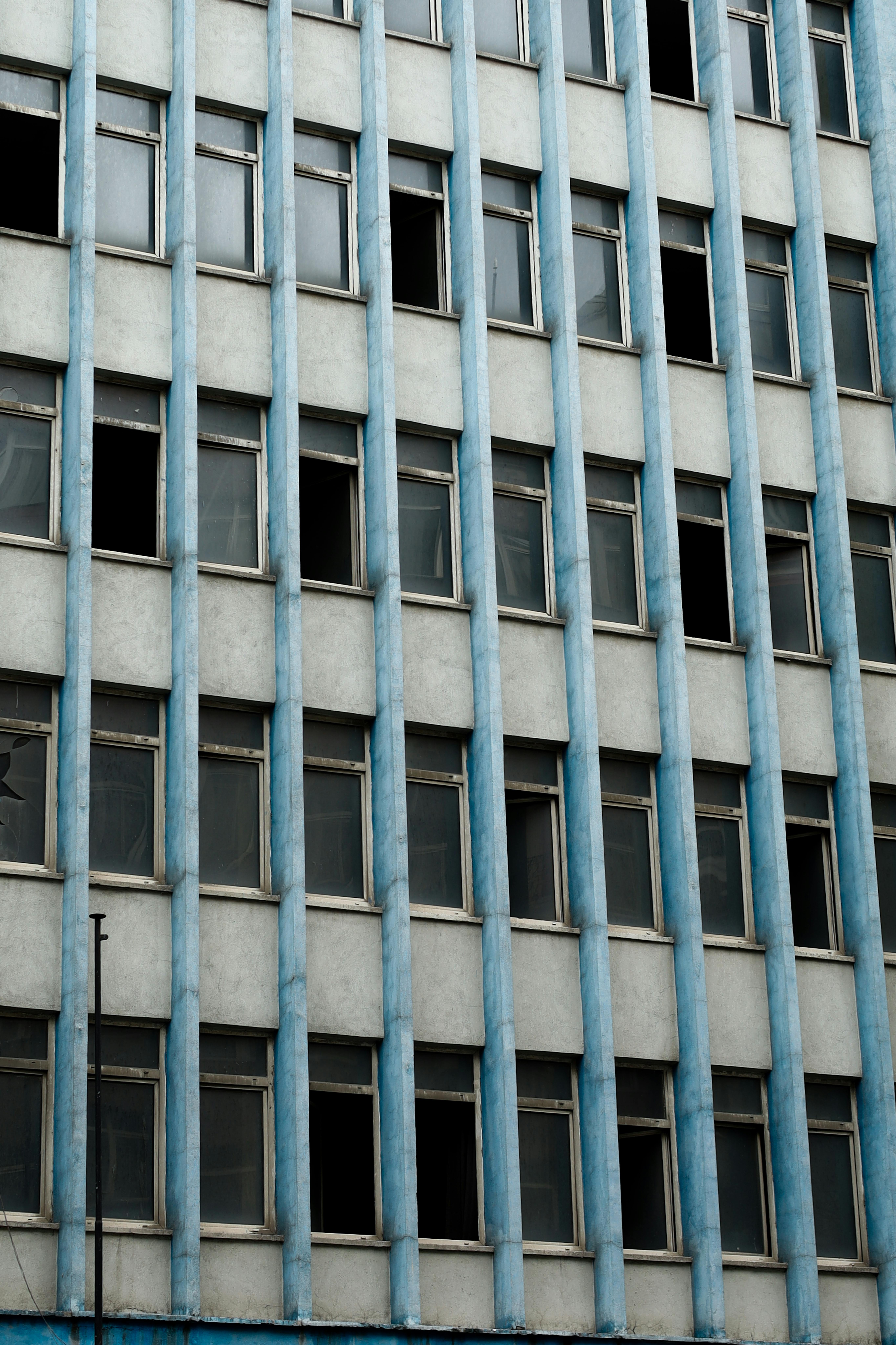 Δωρεάν Κοντινό πλάνο πρόσοψης αστικού κτιρίου με μπλε κολώνες και πολλαπλά παράθυρα. Φωτογραφία από στοκ φωτογραφιών