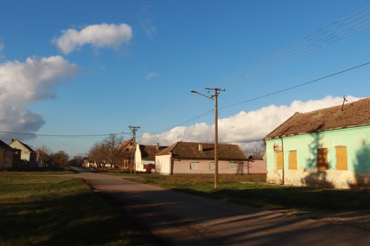 Charming village street scene with rustic houses and clear blue skies.