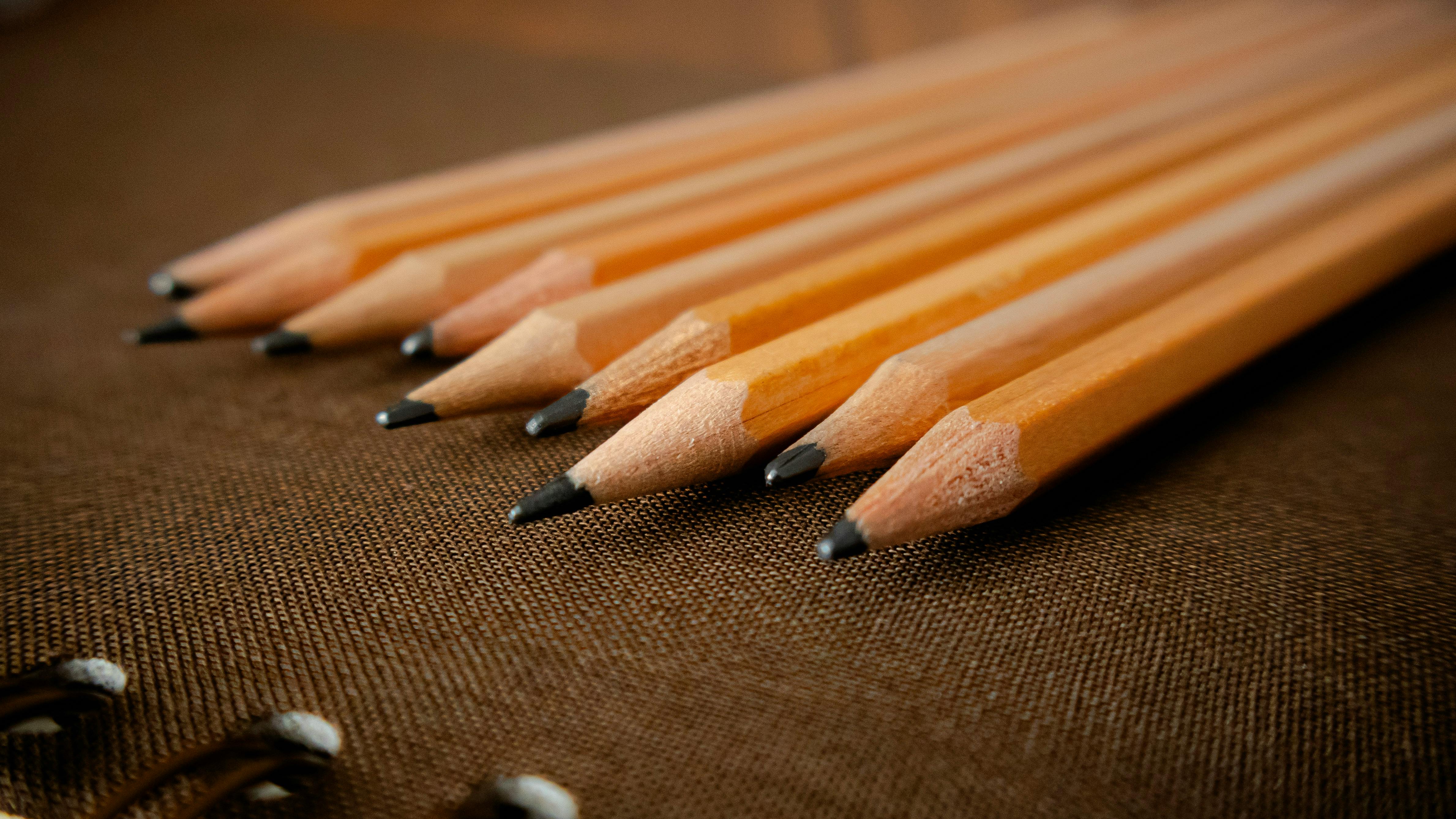 bezplatná Detailní pohled na nabroušené dřevěné tužky umístěné na texturovaném látkovém pozadí, ukazující umělecké zpracování a preciznost. Základová fotografie