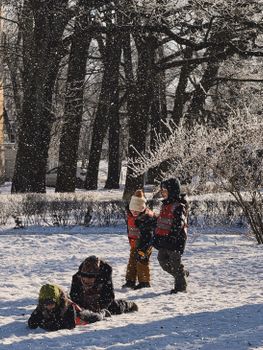 Group of children playing in a snow-covered park in Latvia during winter.