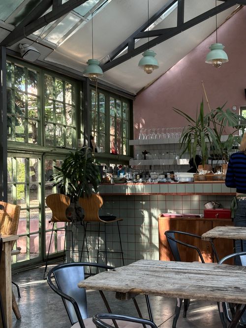 Free Charming café interior with rustic wooden tables and sunlit space, perfect for relaxing afternoons. Stock Photo