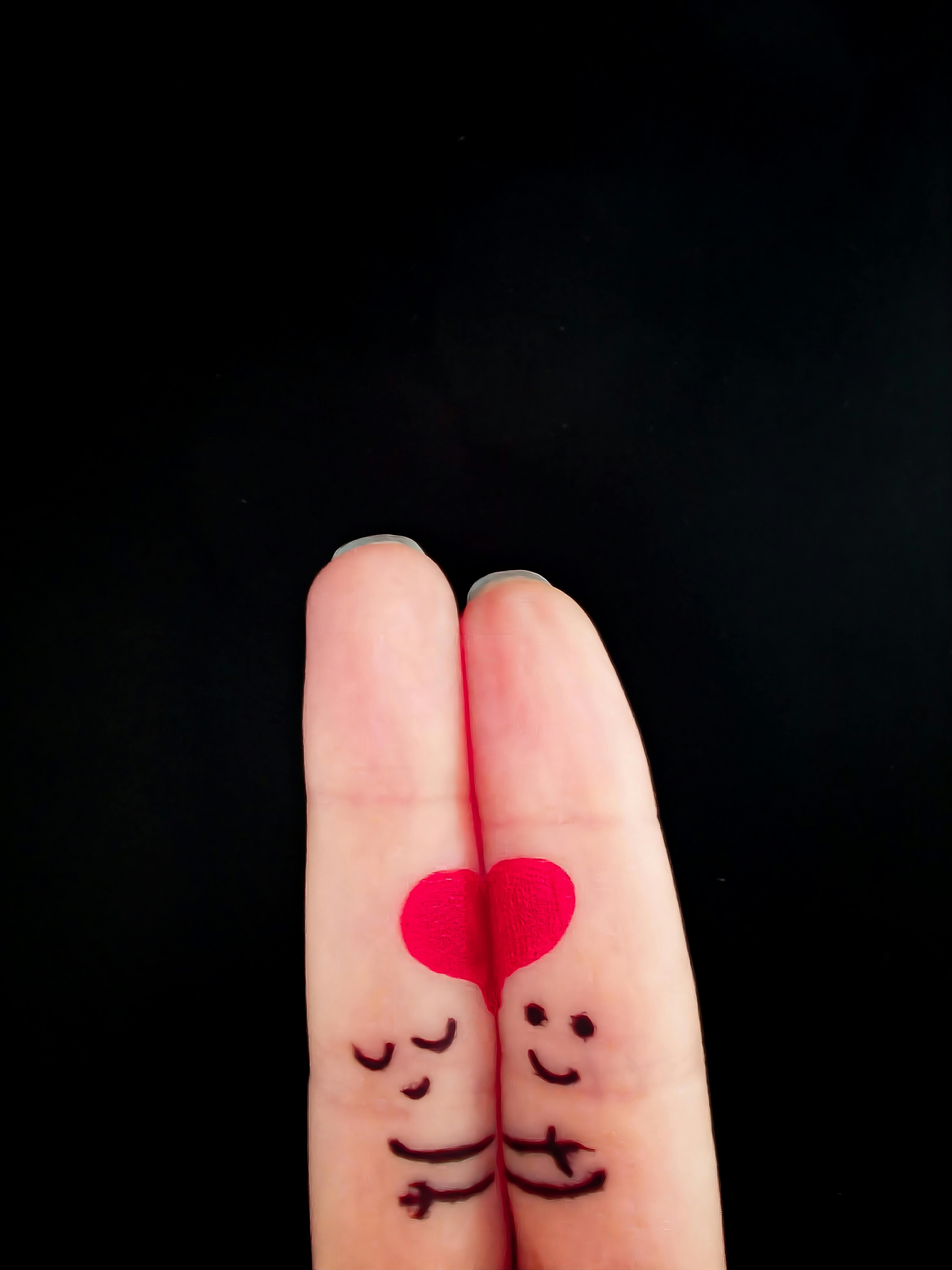 Free Artistic depiction of fingers as a couple with a heart symbol on black background. Stock Photo