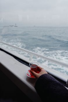 A relaxing moment with Turkish tea on a ferry, overlooking the calm ocean waters.