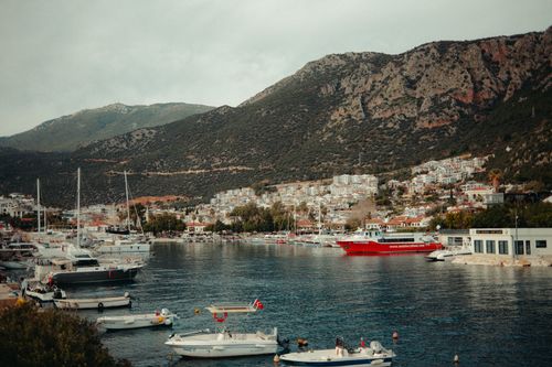 Free Scenic view of a coastal town surrounded by mountains with yachts and boats anchored in the harbor. Stock Photo